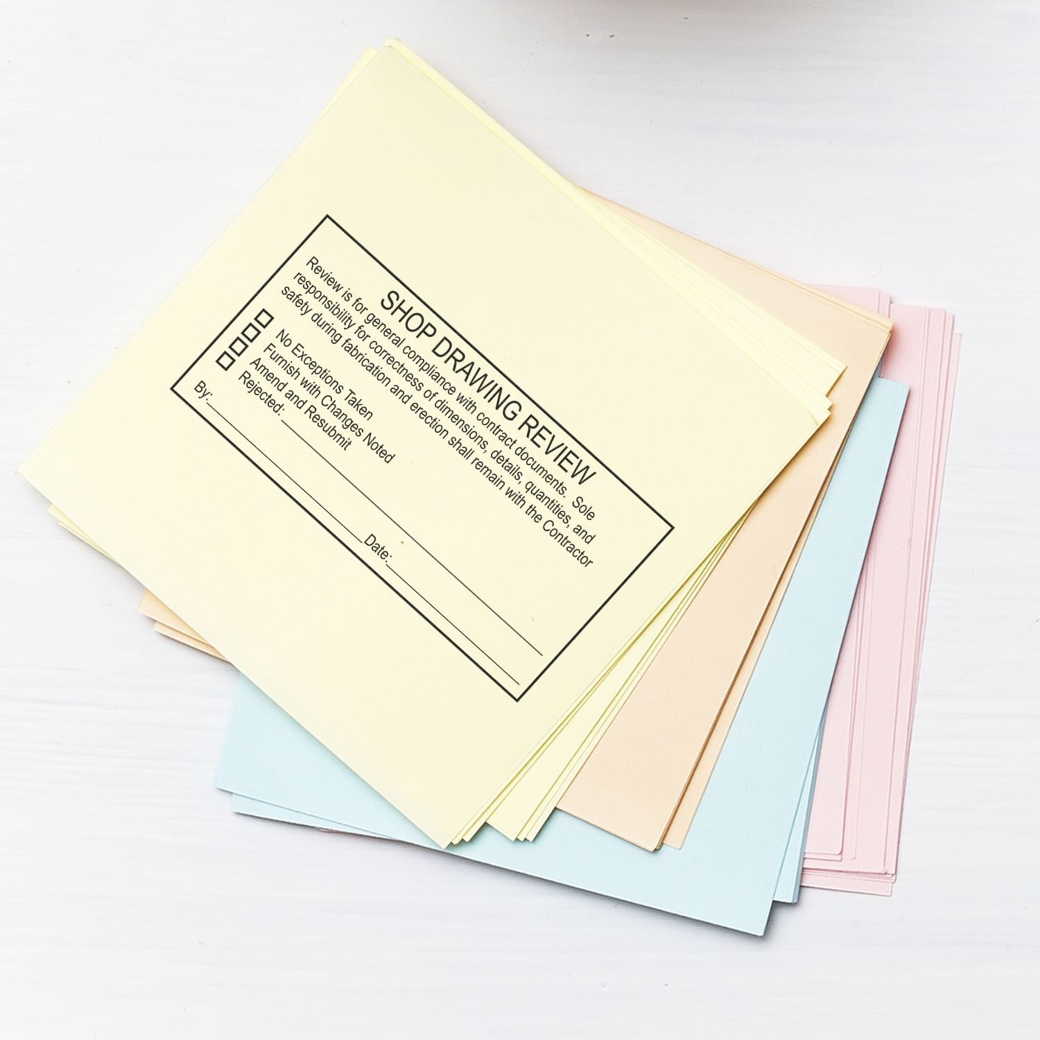 Stack of colorful shop drawing review forms for construction document approval and project review.