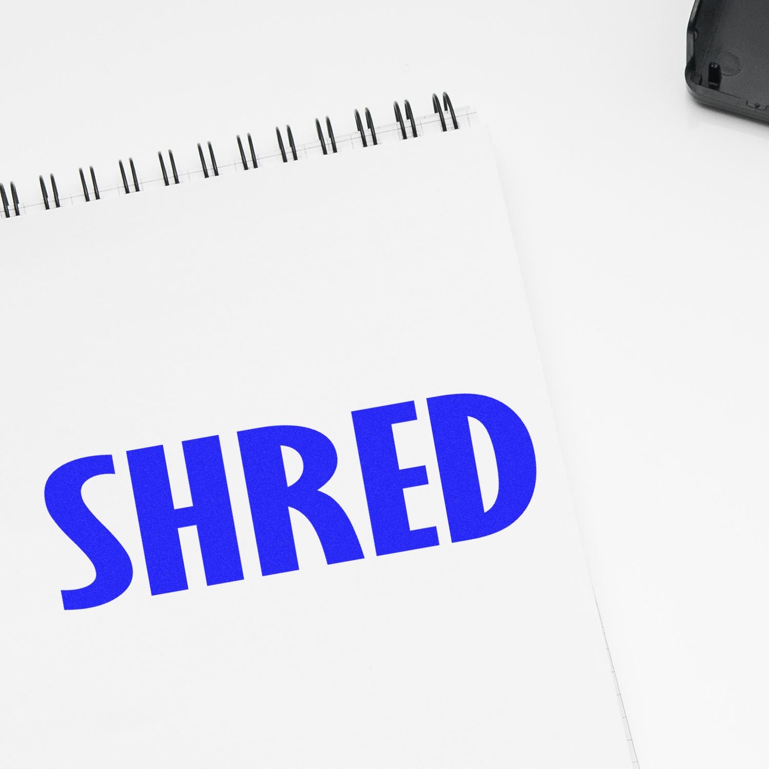 Spiral notebook with bold blue text SHRED, symbolizing document shredding for secure data disposal and privacy compliance.