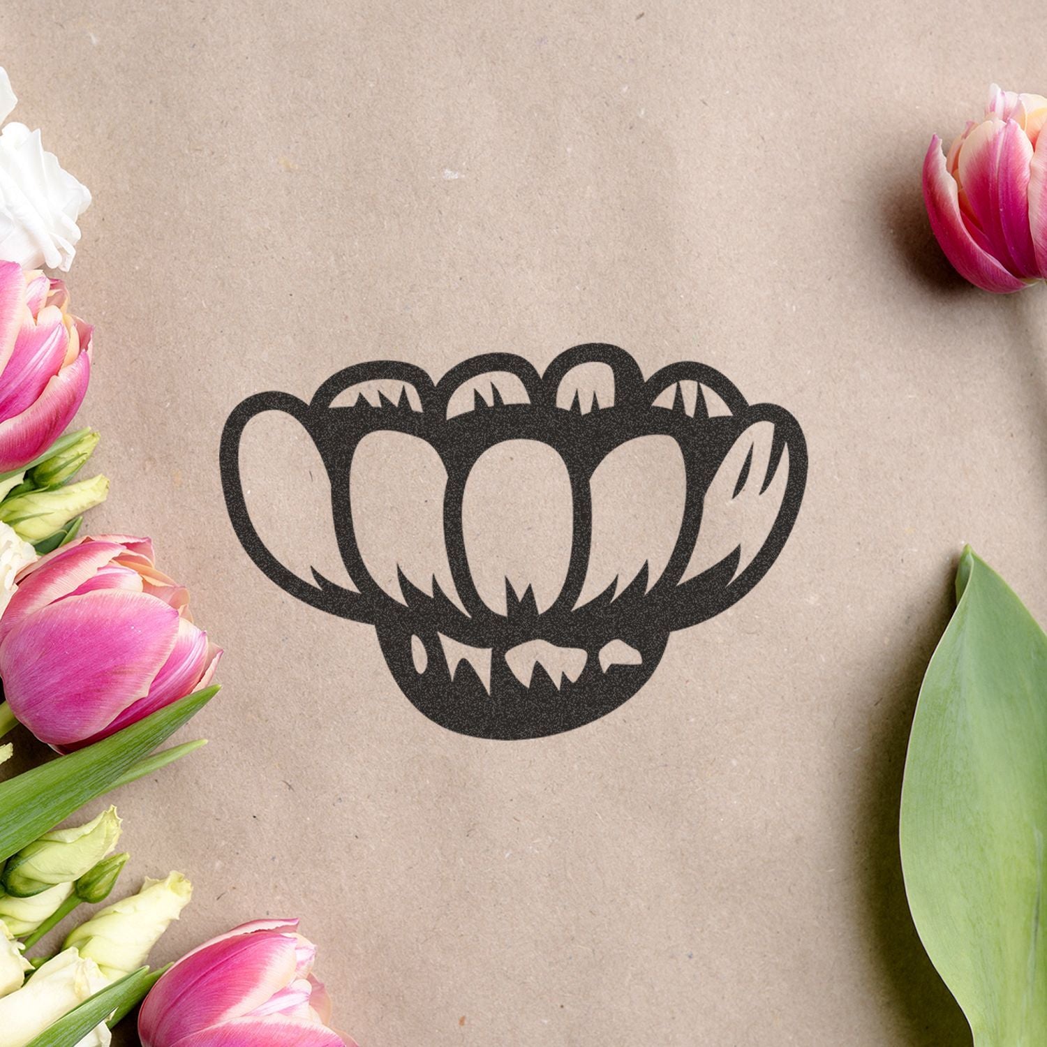 Black floral logo on kraft paper surrounded by pink and white tulips on a spring flat lay background