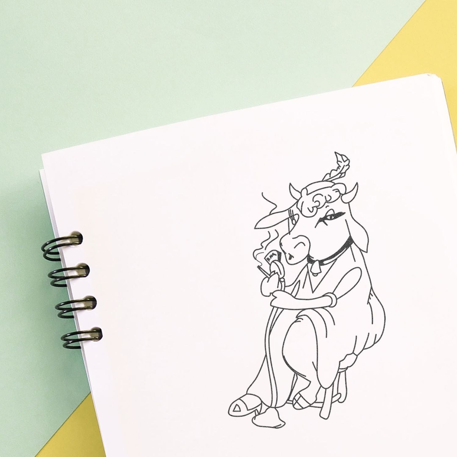 Spiral sketchbook with minimalist cow line art on a pastel green and yellow background