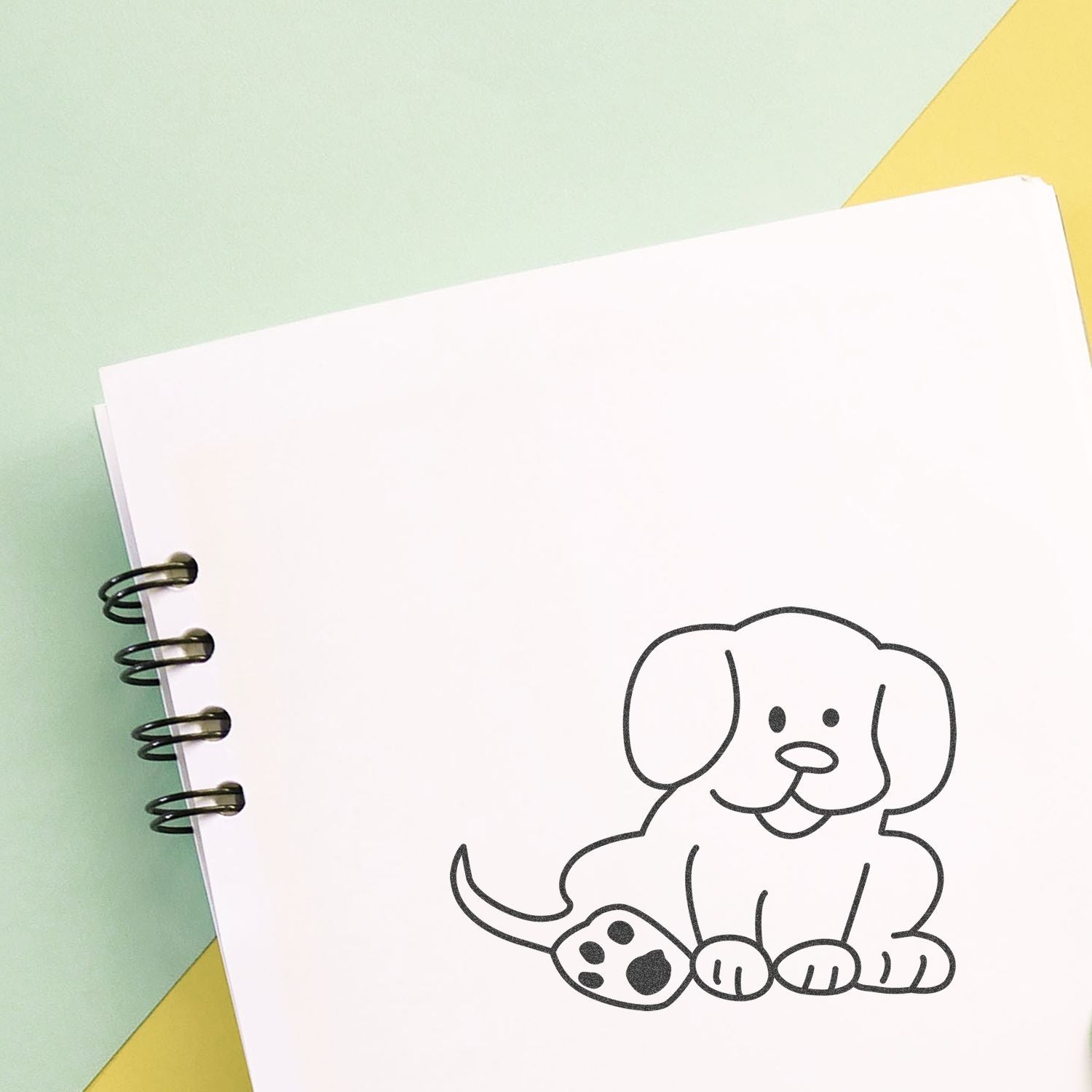 Cute puppy doodle on a spiral notebook page with a pastel green and yellow background.