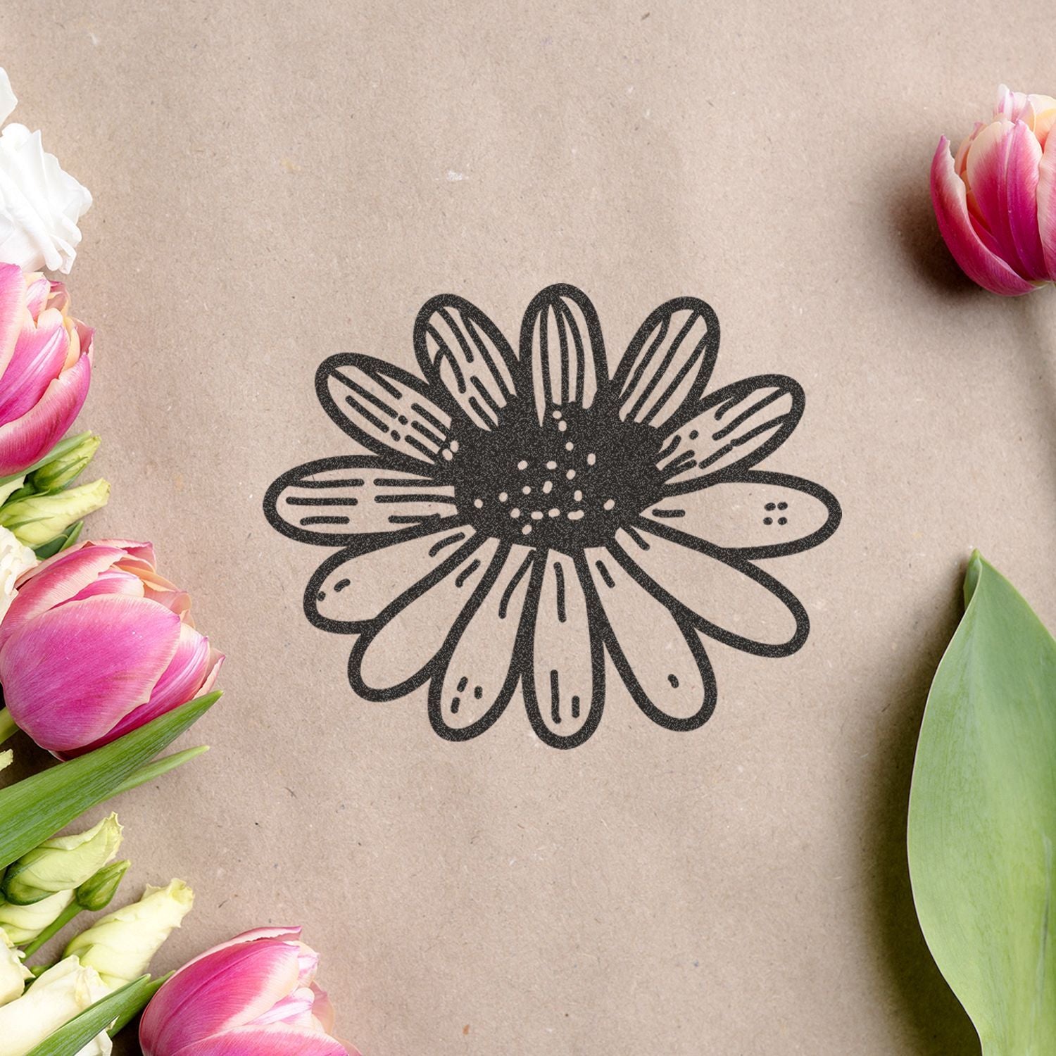 Floral black daisy logo on kraft paper surrounded by pink tulips and white flowers, eco-friendly botanical packaging design.