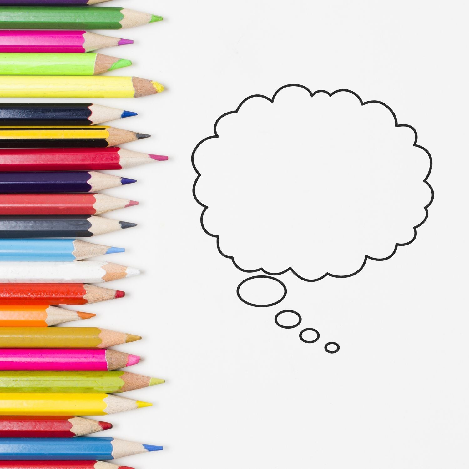 Colorful pencils lined up beside a blank thought bubble on a white background for creative brainstorming and design ideas.