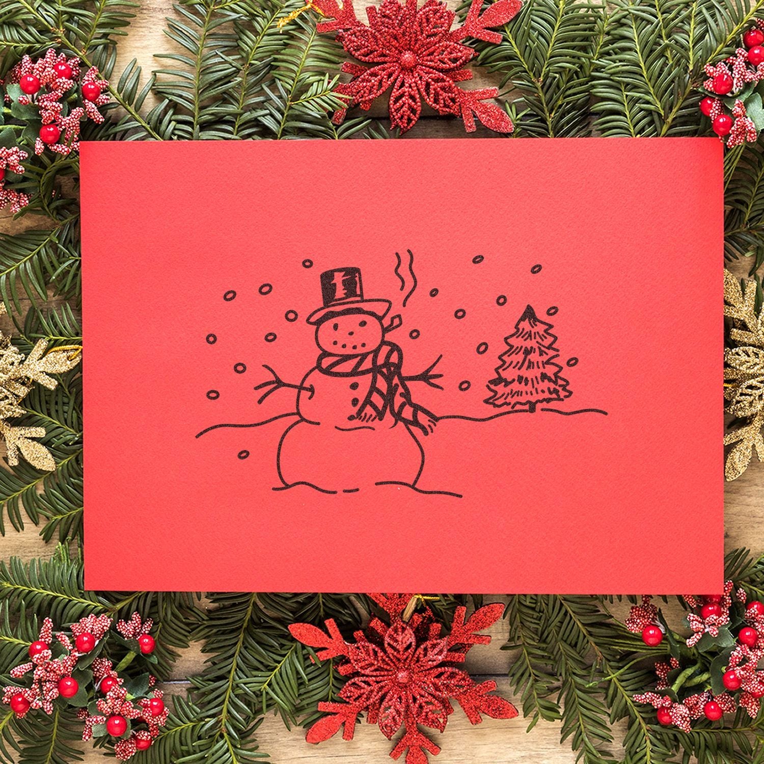 Festive red Christmas card with hand-drawn snowman and pine tree on a holiday wreath background