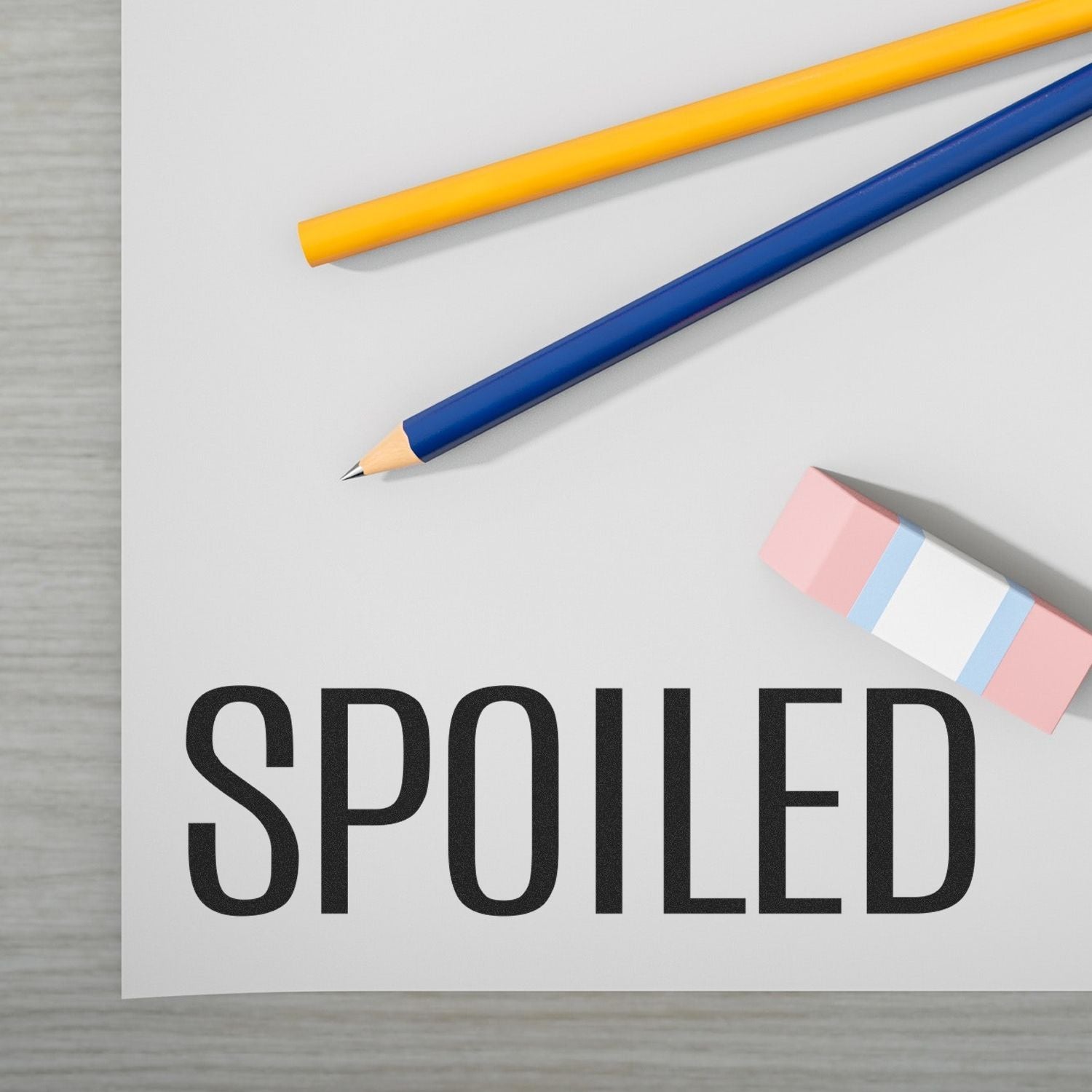 Close-up of the word SPOILED on white paper with pencil and eraser, concept of correction and editing.