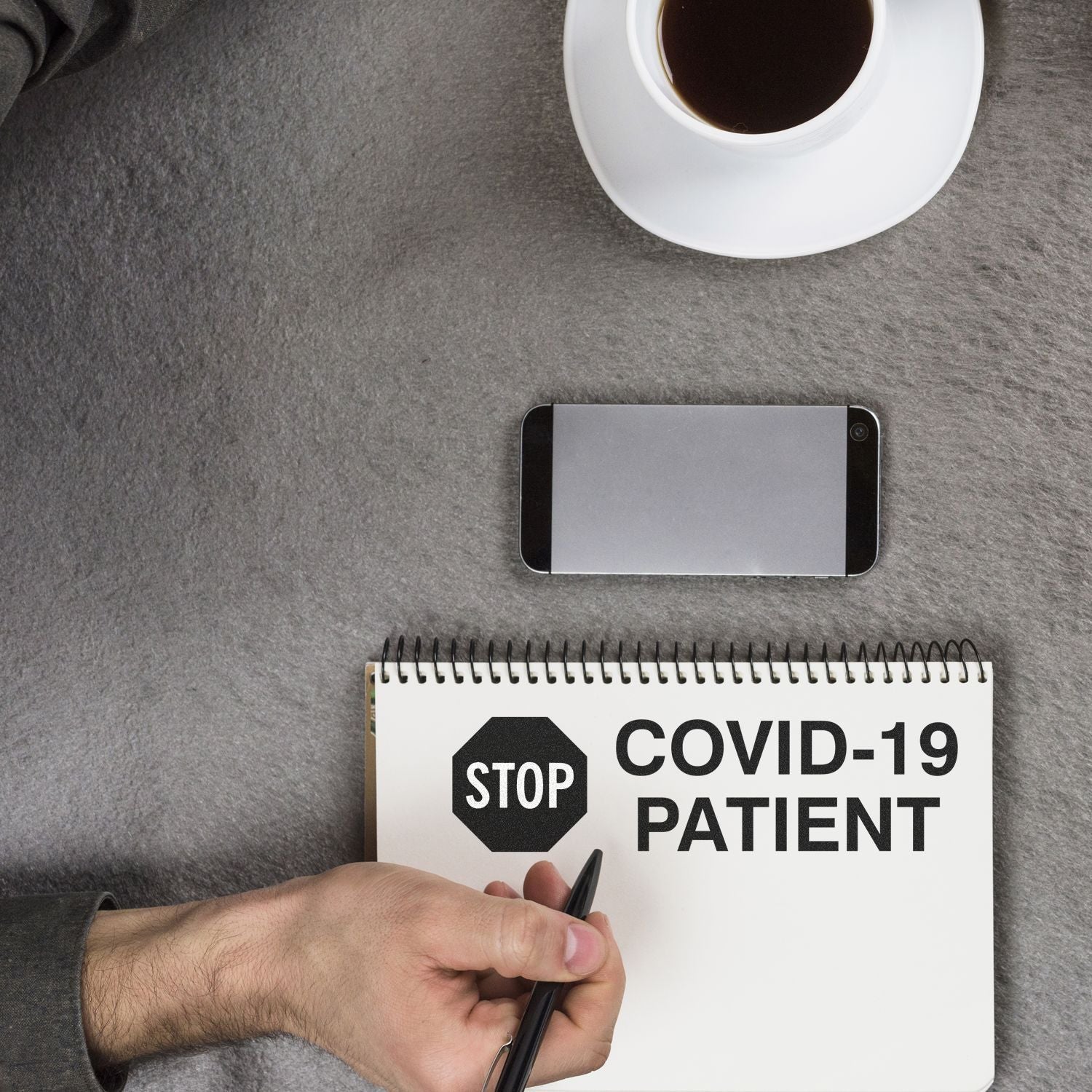 Handwriting COVID-19 patient note with stop sign concept on notebook, smartphone and coffee nearby, preventive care reminder.