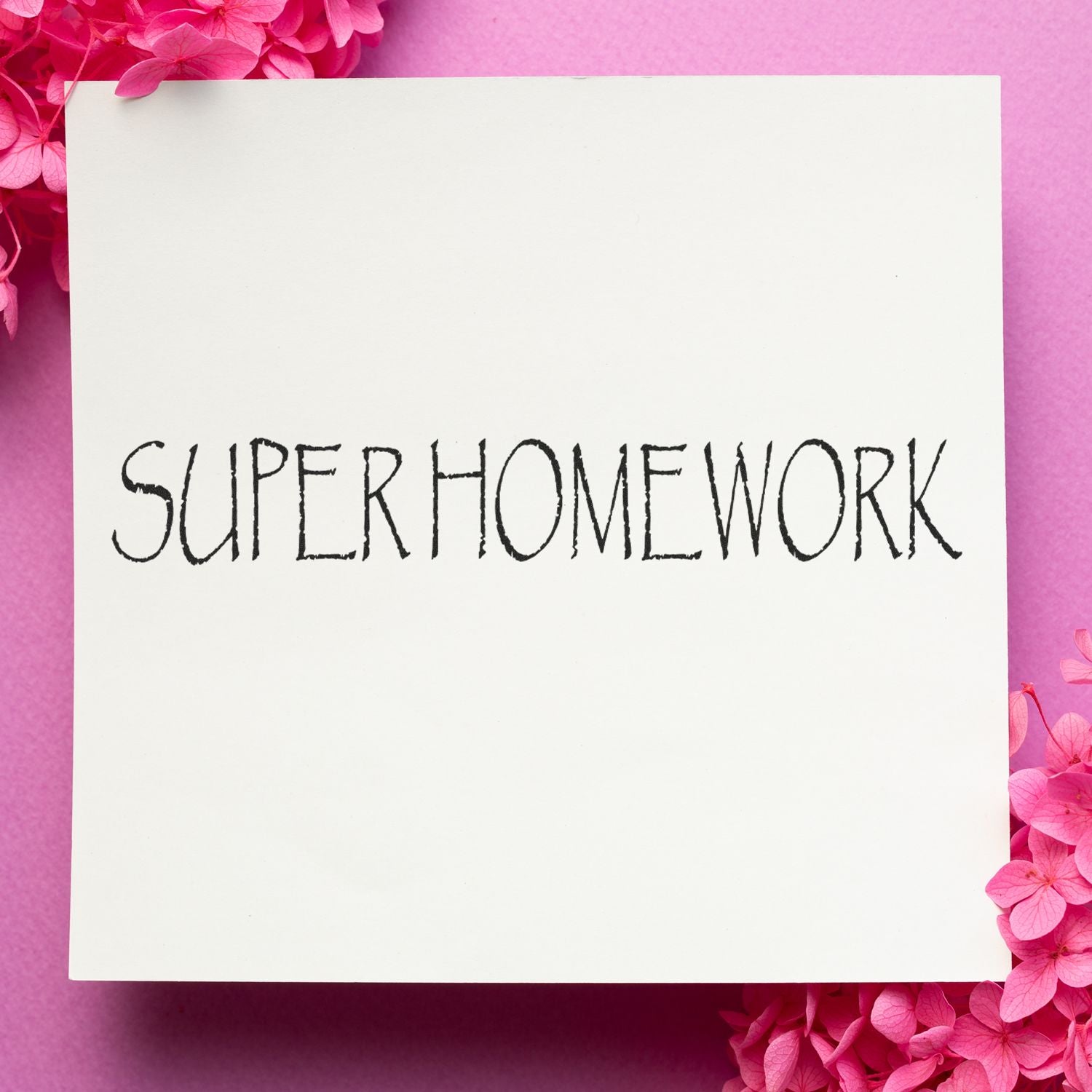 Blank white paper with SUPERHOMEWORK text on a pink floral background, creative school homework concept.