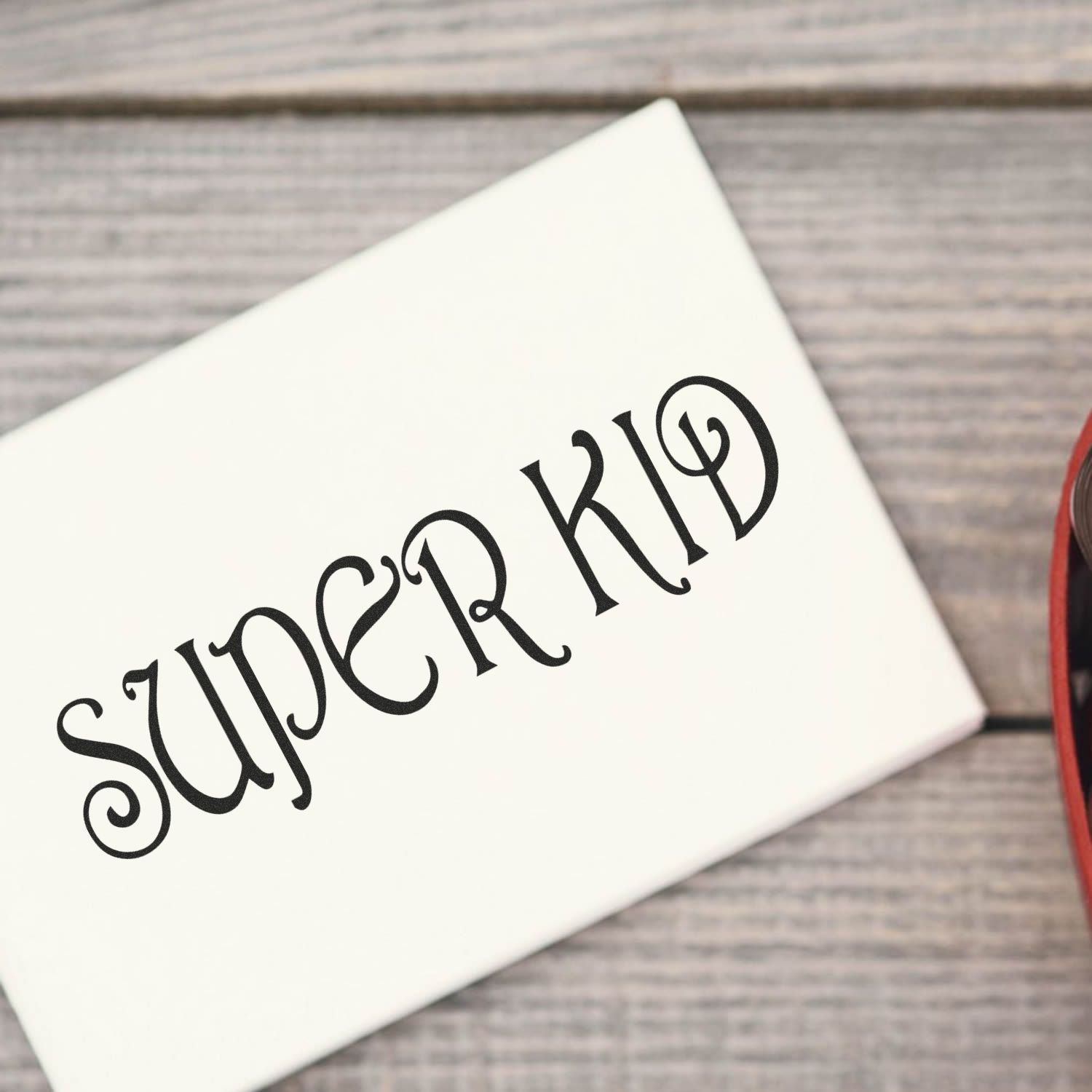 White Super Kid decorative vinyl decal on a wooden background, custom kids room wall or laptop sticker design.