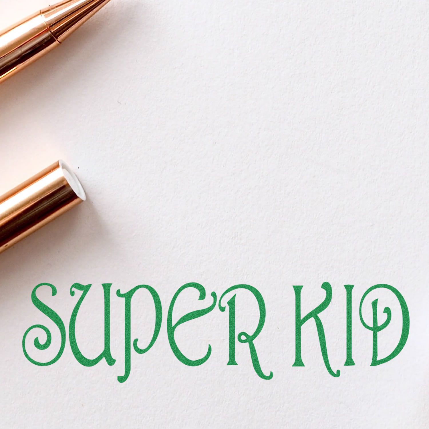Stylish green Super Kid text on white paper with rose gold pens, modern kids branding design.