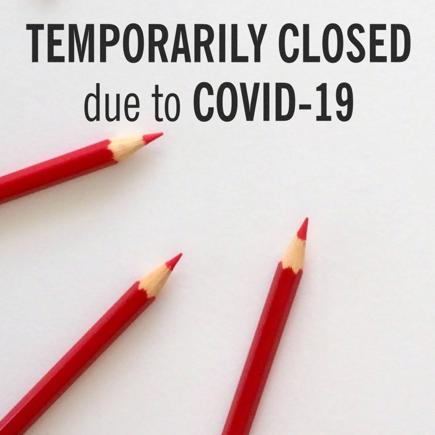 Temporarily closed due to COVID-19 sign with red pencils on white background, showing business shutdown during the coronavirus pandemic.