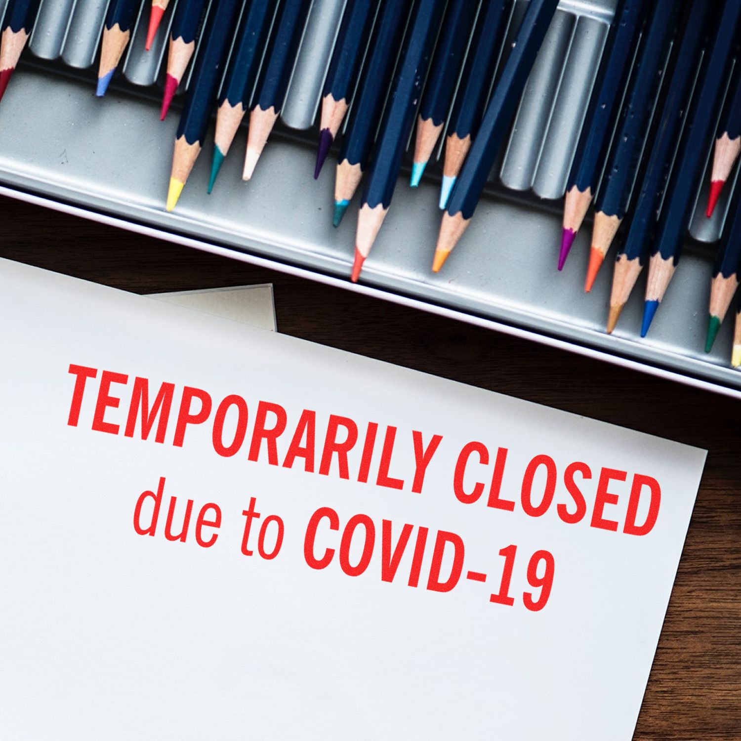 Temporarily closed due to COVID-19 sign with colored pencils, illustrating school or business closure during the coronavirus pandemic.