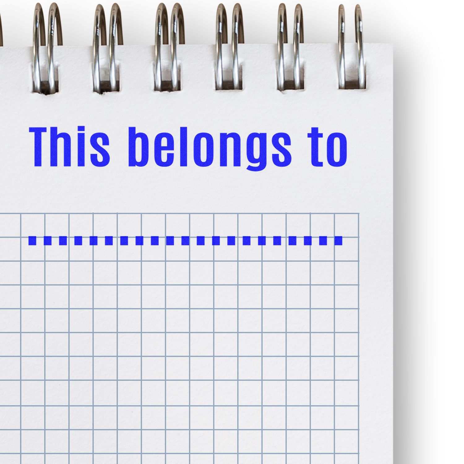 Stationery label reading This belongs to with binder clips over a ruled notebook grid background