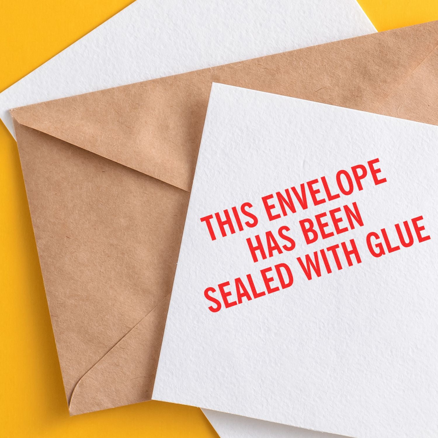 Closed kraft envelope with white card reading This envelope has been sealed with glue on a yellow background.