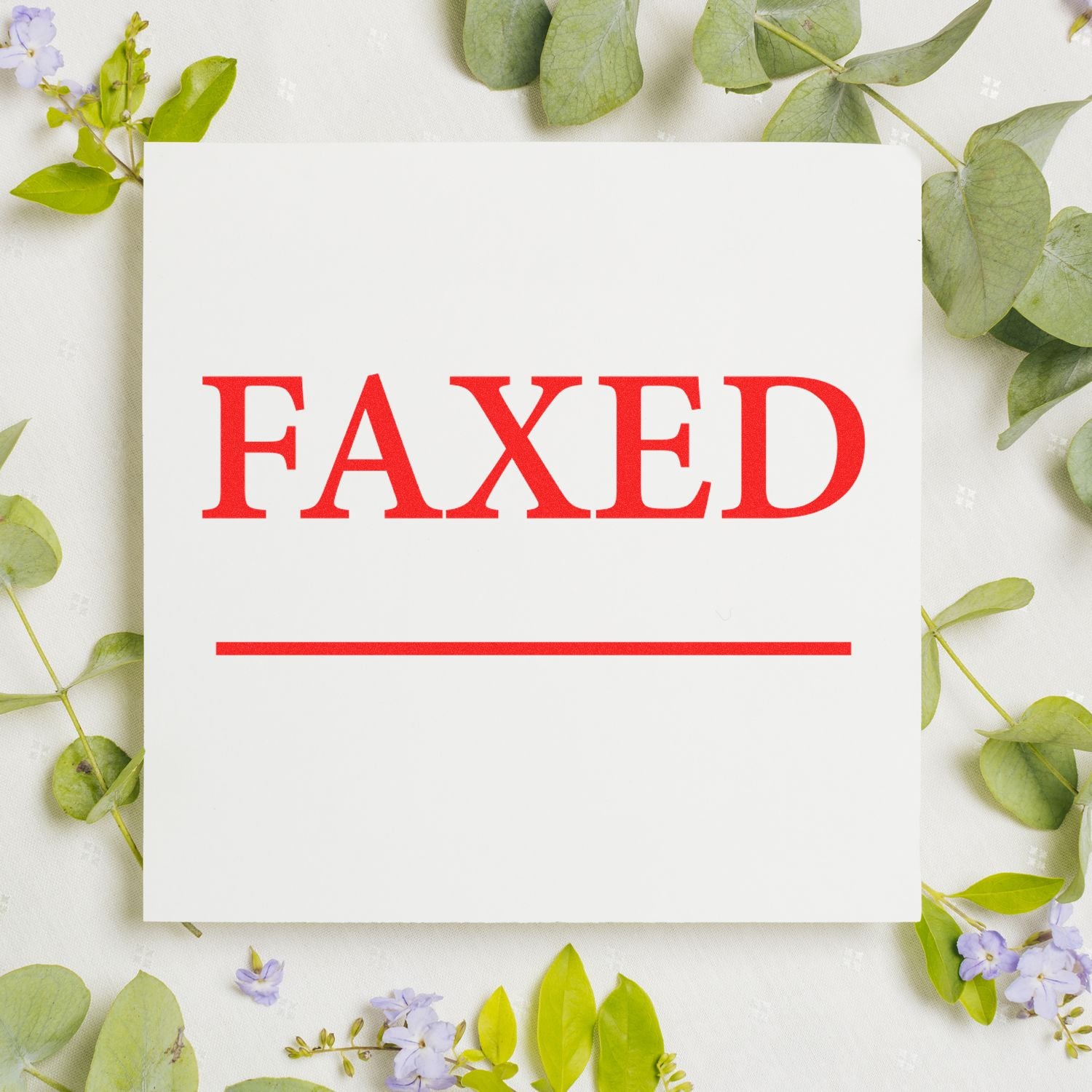 White paper card with bold red FAXED text, surrounded by green eucalyptus leaves and small purple flowers.