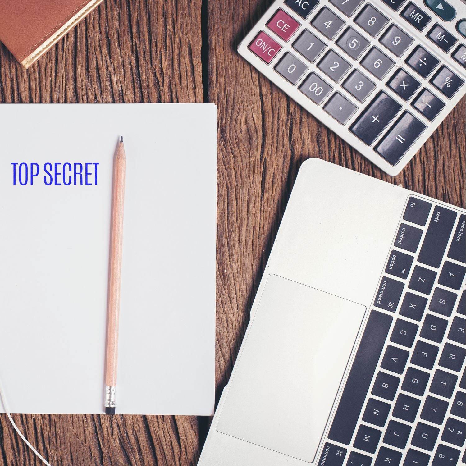 Top secret notebook with pencil, calculator, and laptop on a wooden desk, office workspace concept