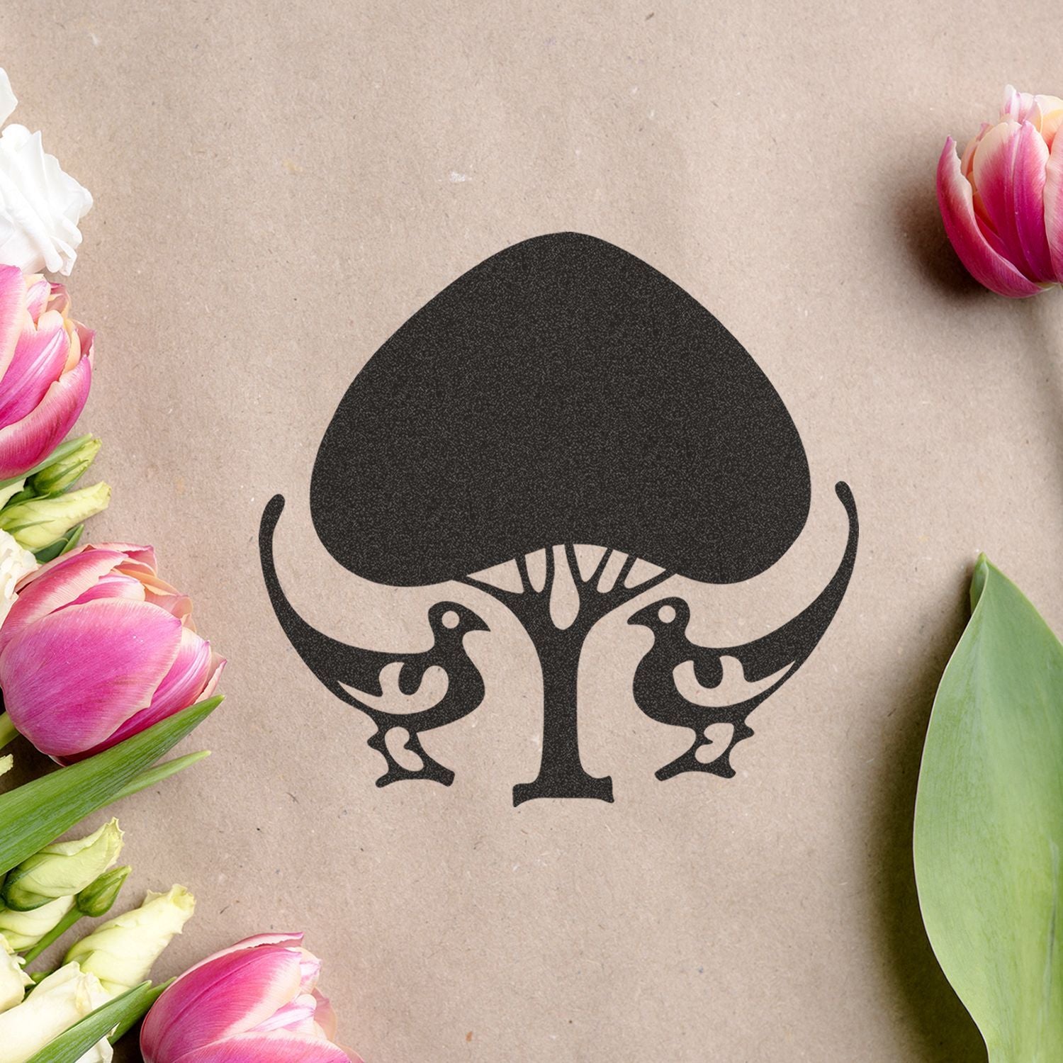 Black tree and two birds logo on kraft paper with pink tulips, natural floral branding design