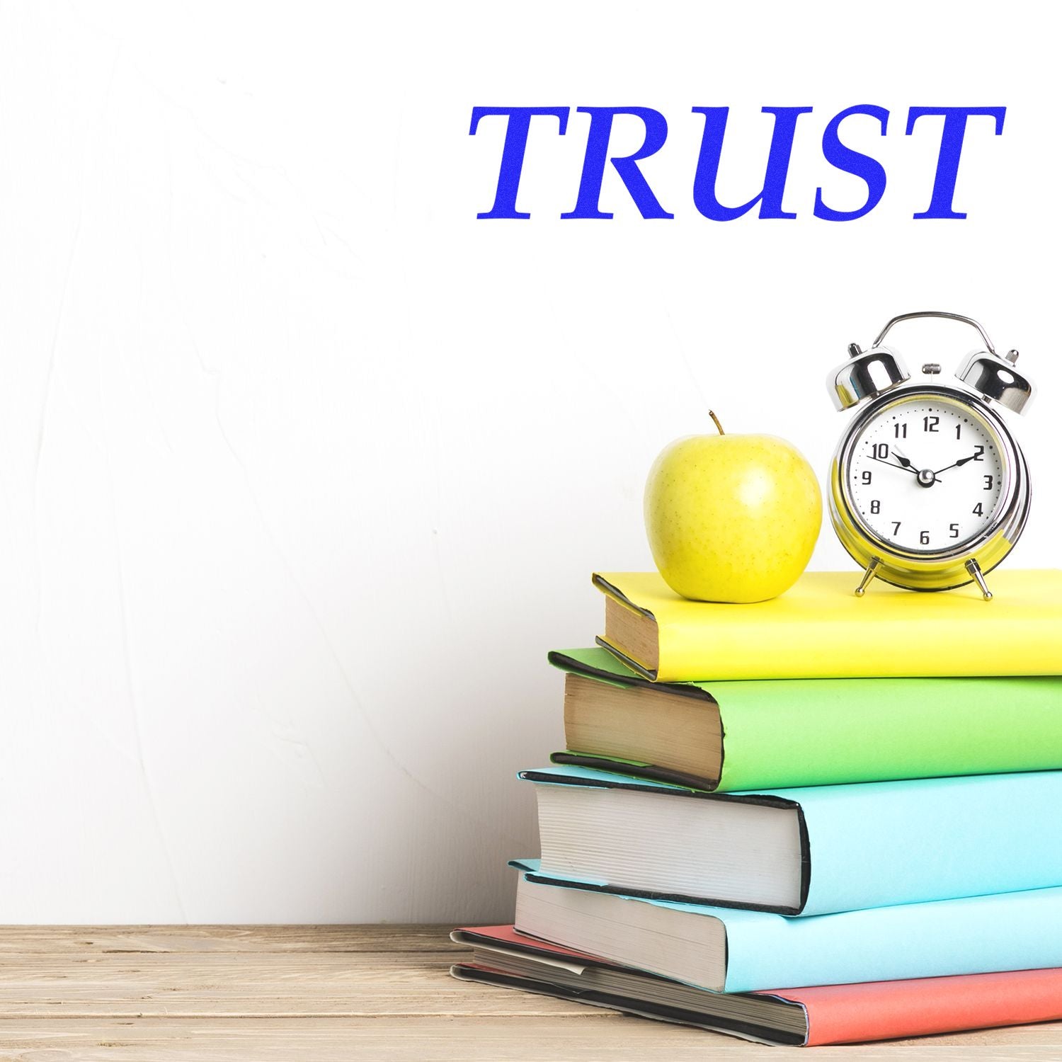 Trust concept with stack of colorful books, apple, and alarm clock on wooden desk.