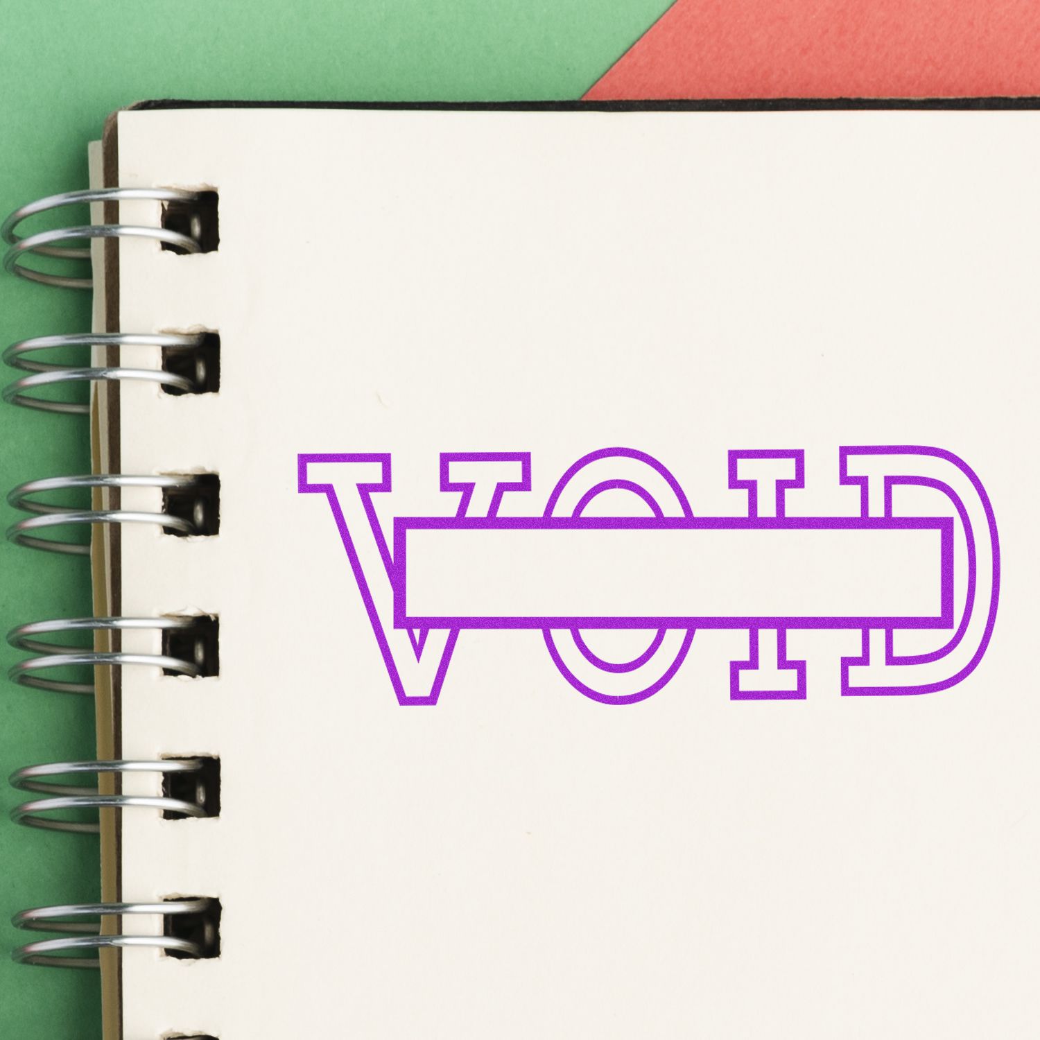 Spiral notebook page with bold purple VOID text and blank label on a colorful green and red paper background.