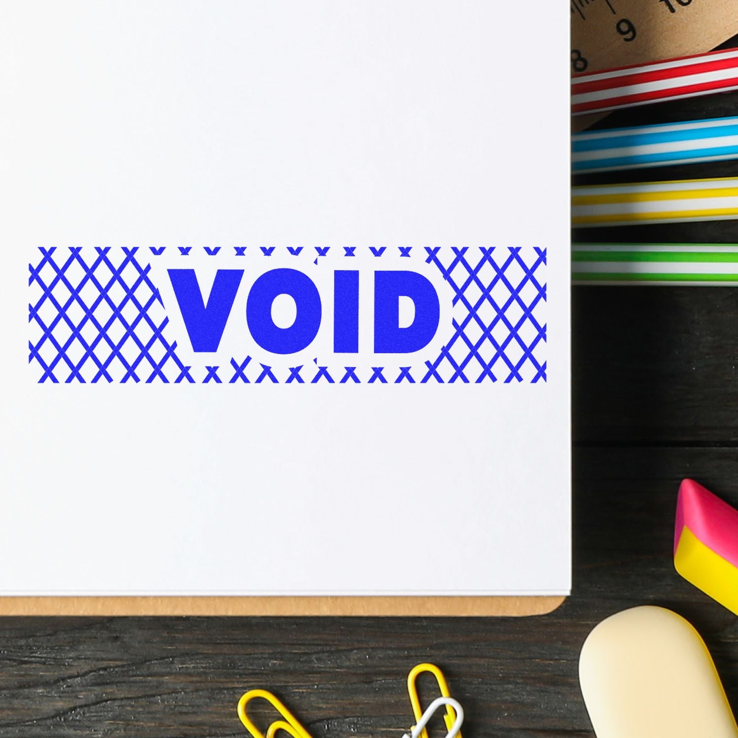 White notebook cover with bold blue VOID text on a desk with colorful stationery supplies.