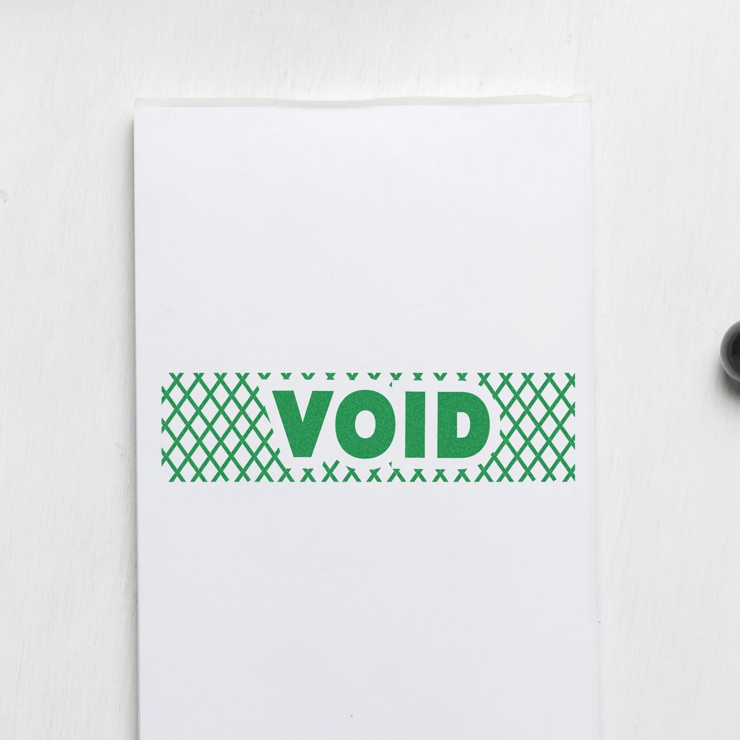 White stationery cover with green VOID wordmark and X-pattern border, product branding close-up.