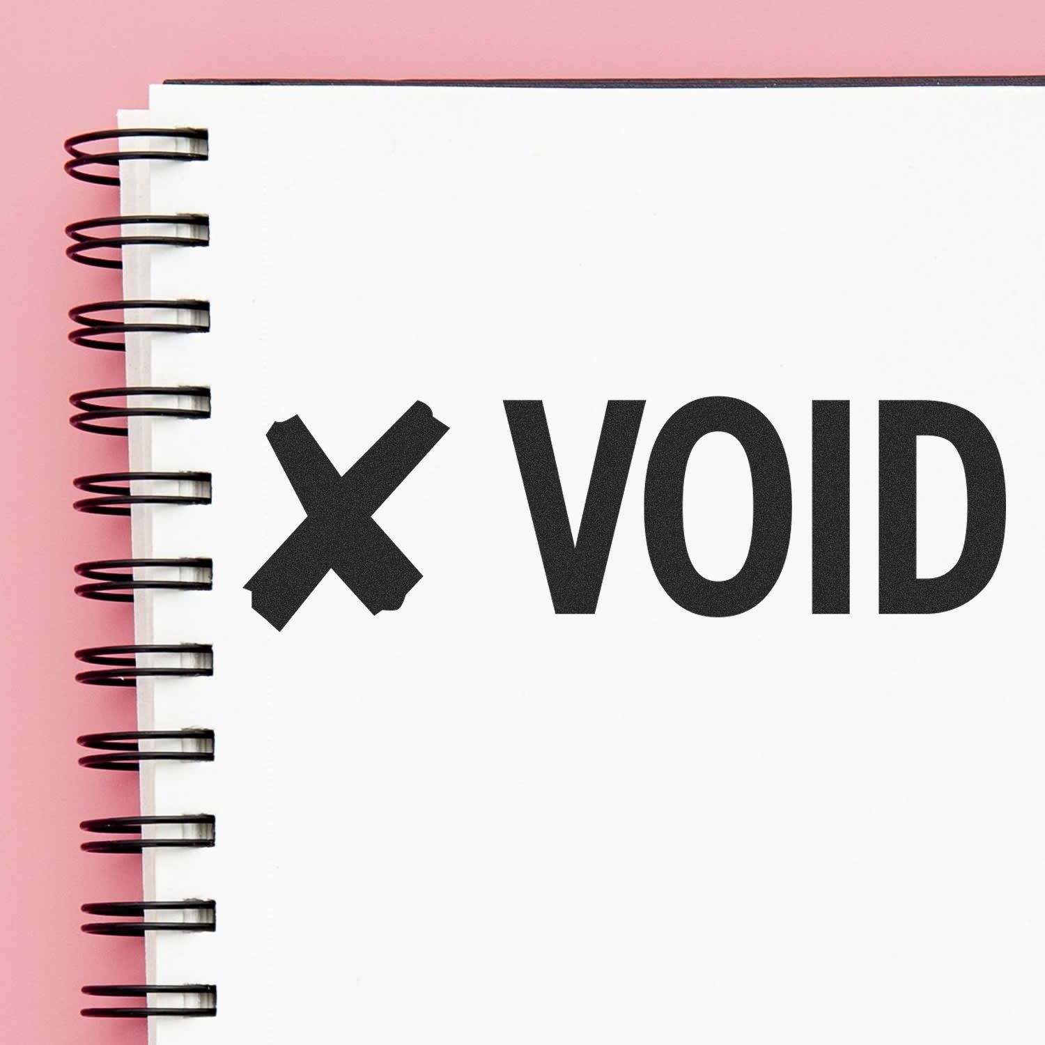 Minimal spiral notebook with bold X VOID text on a blank white page against a pink background