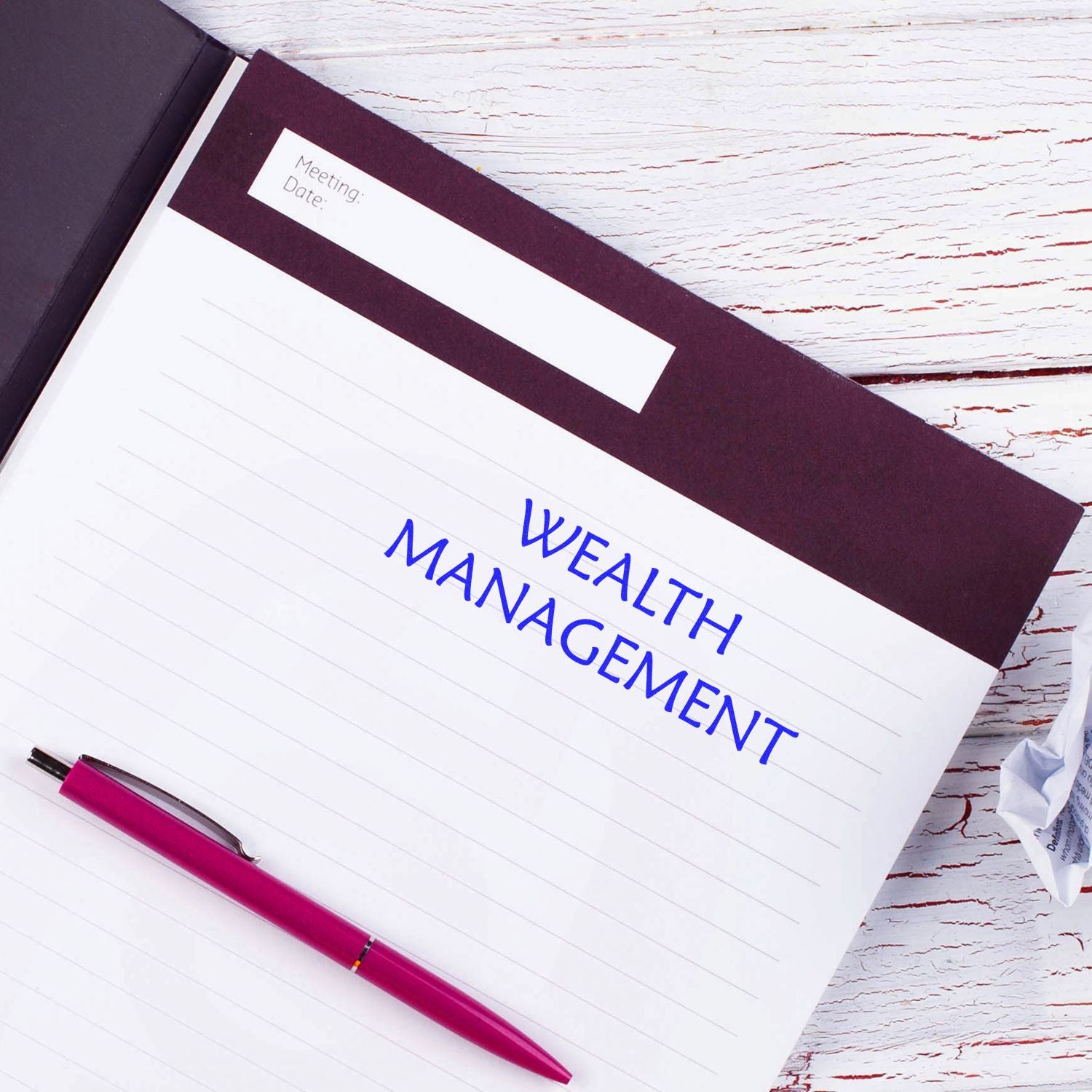 Notebook page labeled Wealth Management with meeting date, set on wooden background with pen, illustrating financial planning strategy.