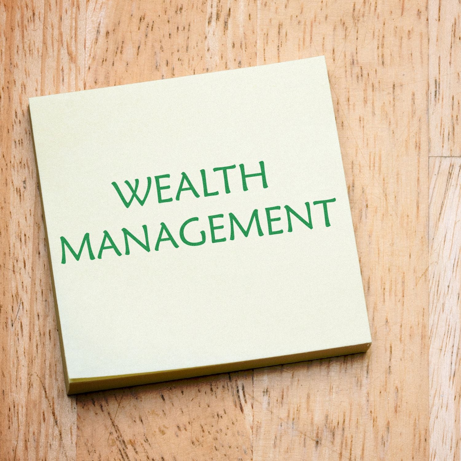 Wealth management concept: white card reading WEALTH MANAGEMENT in green letters on rustic wooden background.