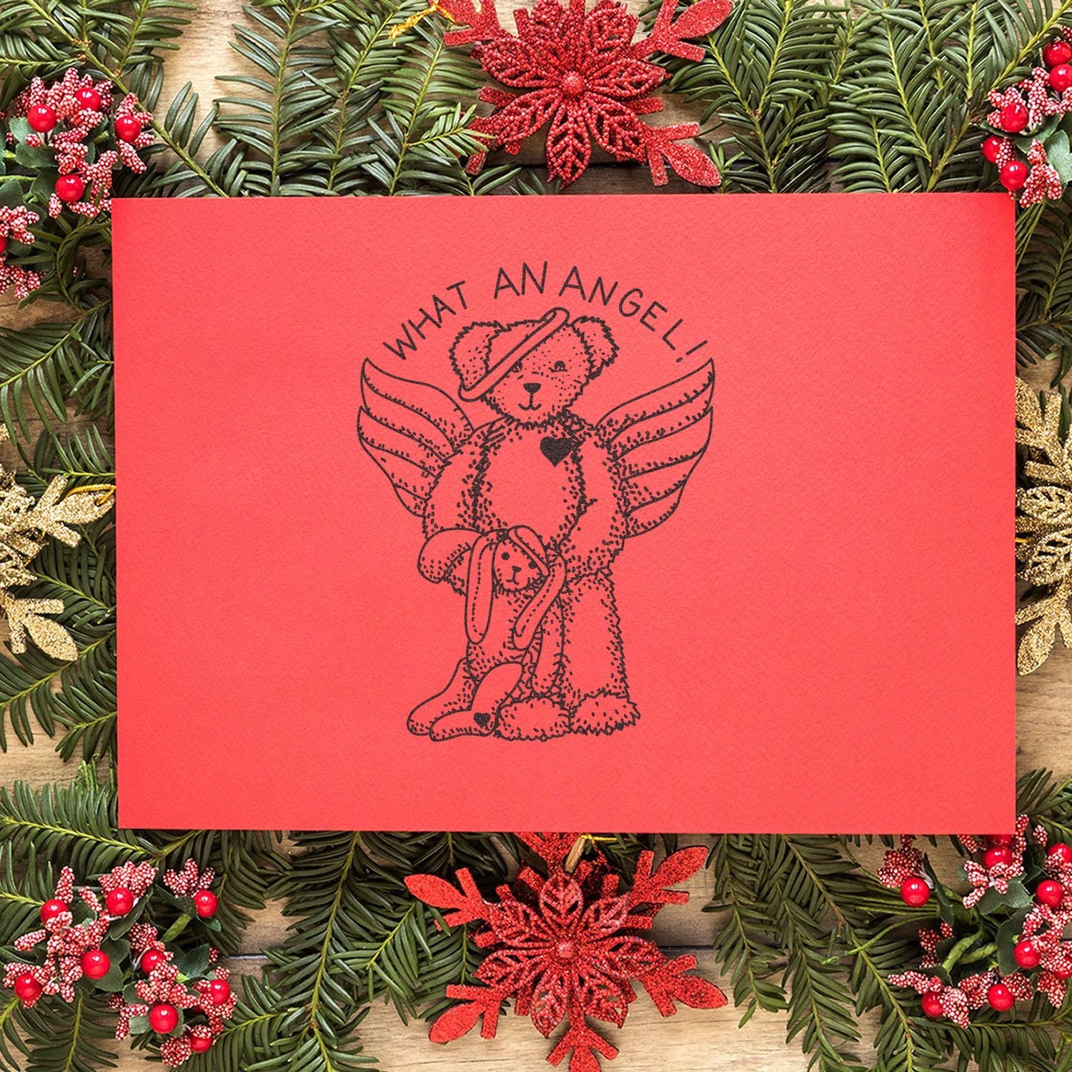 Festive Christmas card with angel teddy bears and angel wings on a red background, surrounded by pine greenery and holiday decorations.