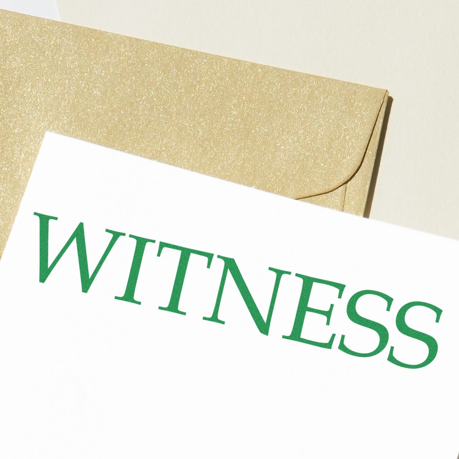 Green WITNESS lettering on a white card inside a gold glitter envelope, indicating legal witness document identification.