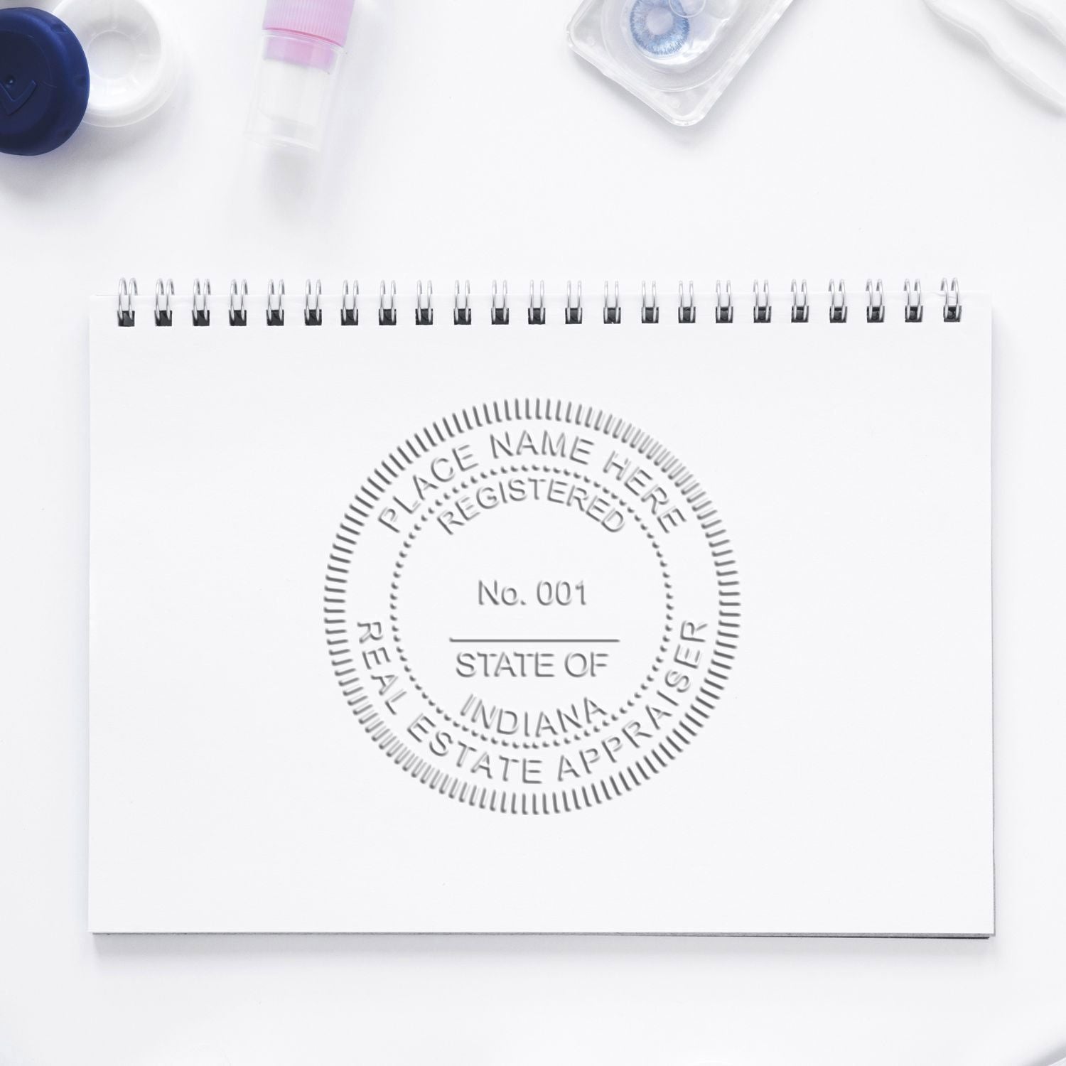 Spiral notebook with embossed Indiana real estate appraiser seal on a clean white desk background.