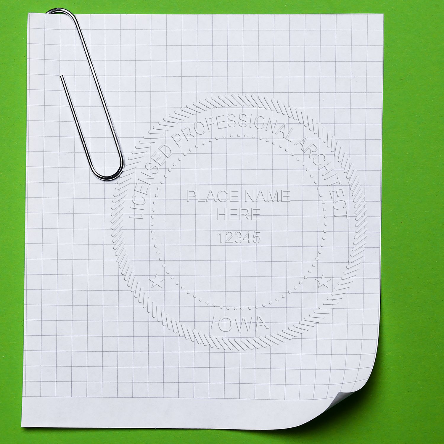 White grid paper with paperclip and embossed architectural seal template on a green background.