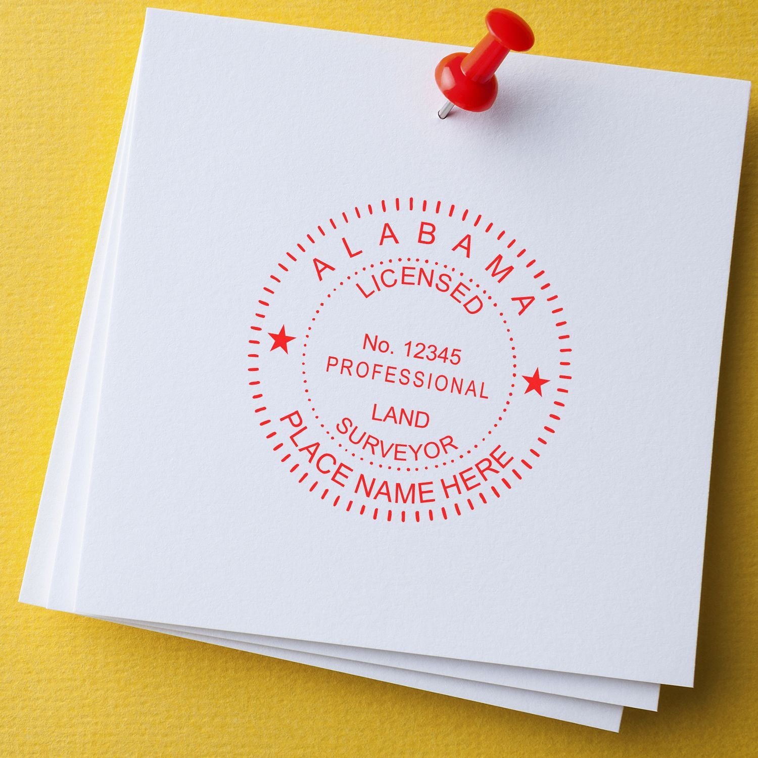 Red Alabama licensed professional land surveyor stamp on white paperwork with a pushpin on a yellow background.
