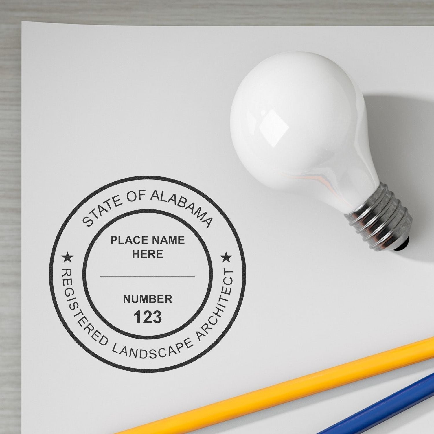 Custom Alabama registered landscape architect seal stamp mockup with light bulb and pencils on white paper