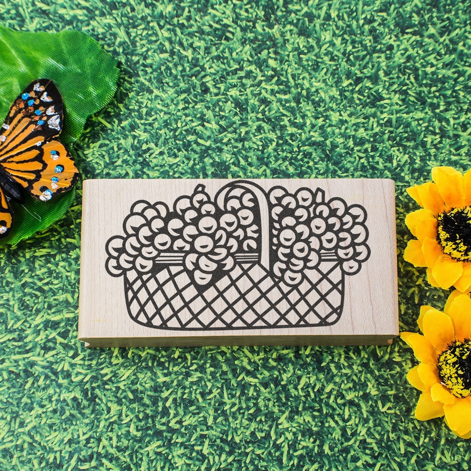 Wooden fruit basket stamp on green grass background with butterfly and sunflower decorations.