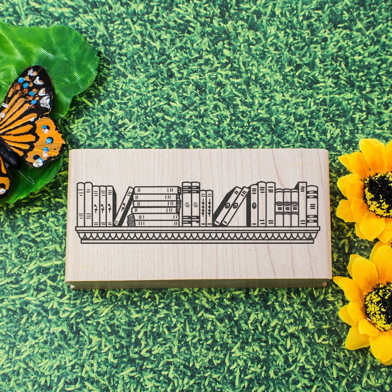 Wooden bookshelf stamp on grass background with butterfly and sunflower accents, rustic home decor design