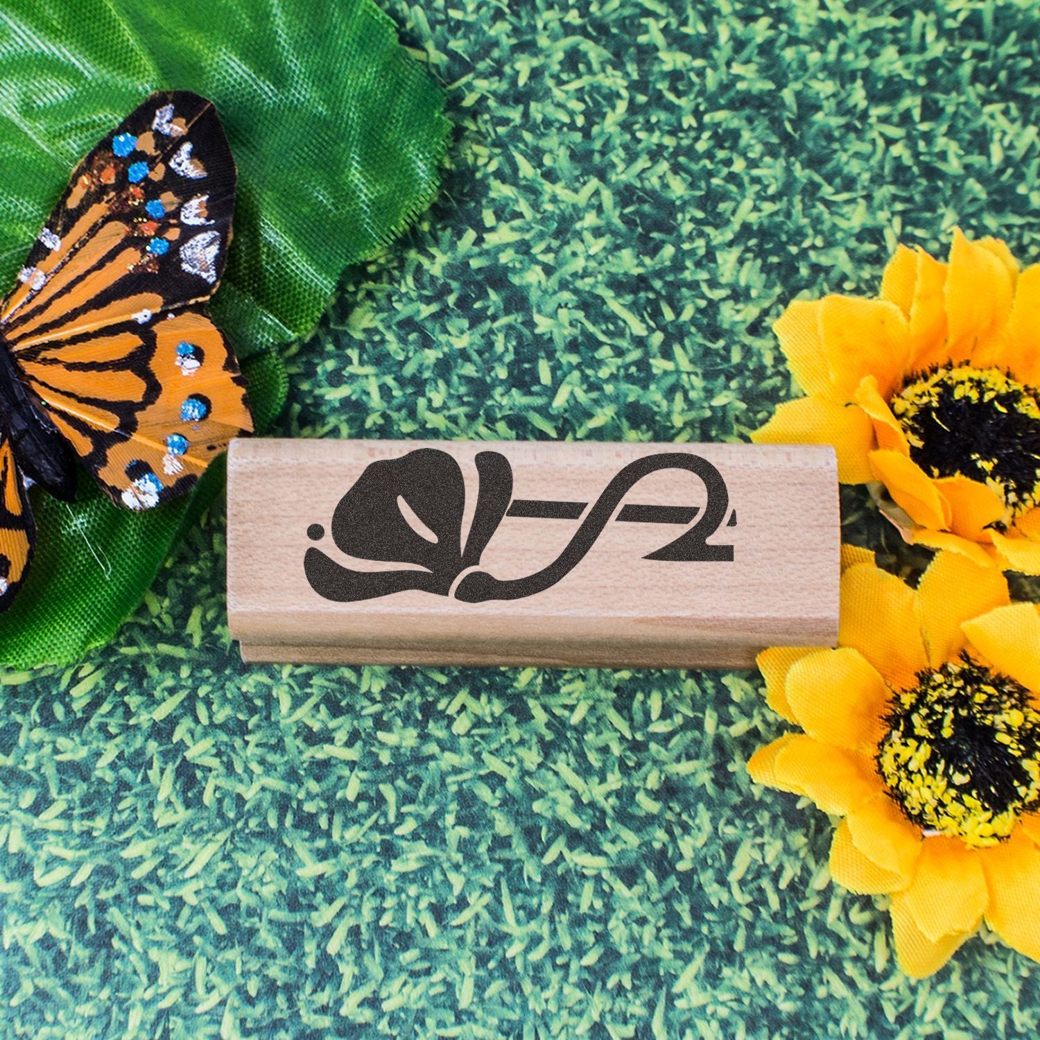 Butterfly-themed wooden stamp with colorful monarch butterfly, sunflower decorations, and green floral background.