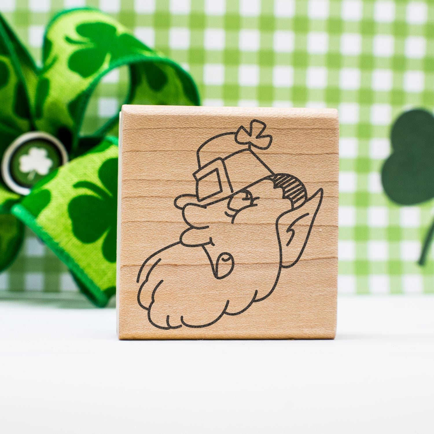 Wooden leprechaun stamp with St. Patricks Day design on green shamrock background.