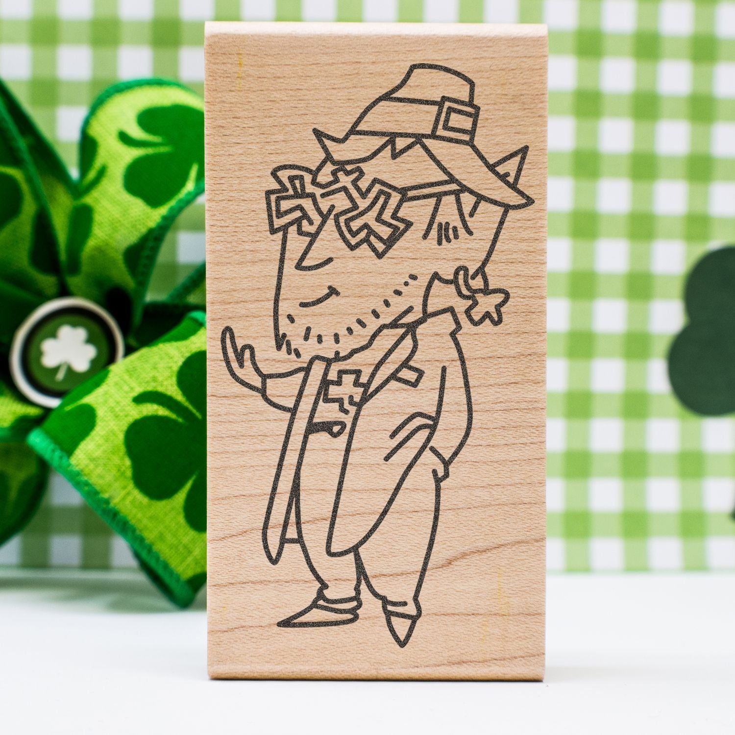 Wooden leprechaun stamp with St. Patricks Day design and green clover background.