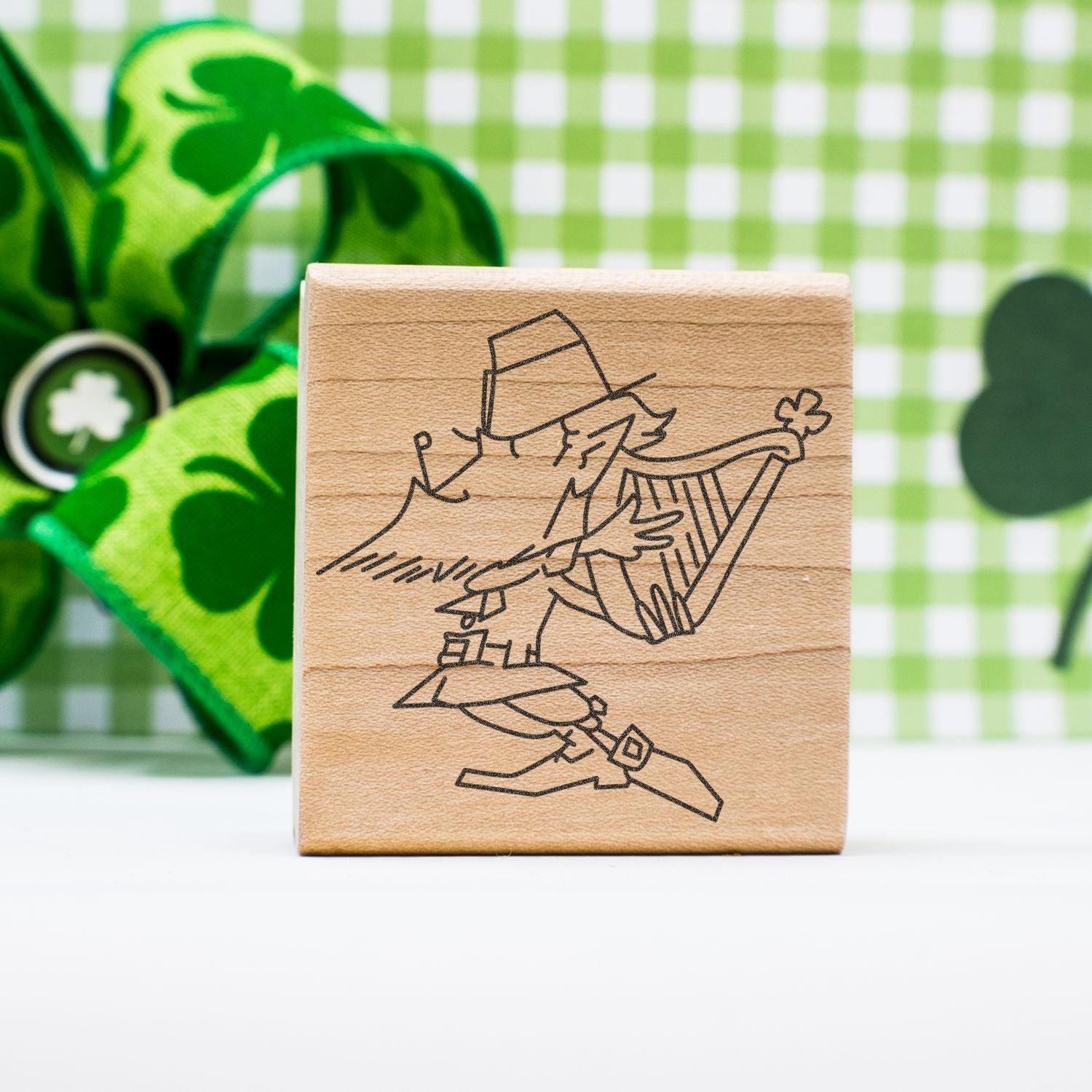 Wooden St. Patricks Day stamp with leprechaun and shamrock design on a green checkered background