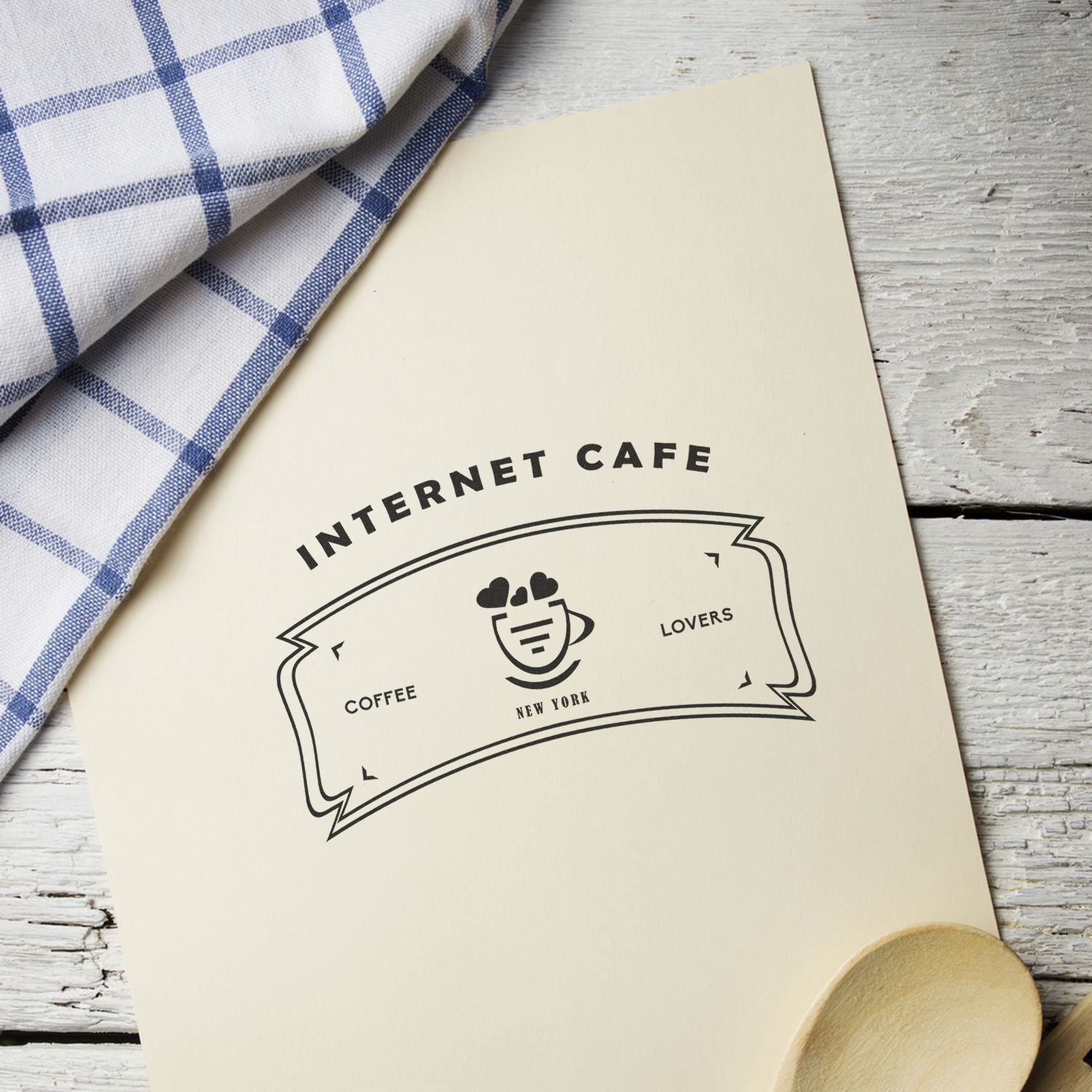 Internet caf coffee logo on cream paper card reading Internet Cafe and New York Lovers, beside blue checkered cloth.