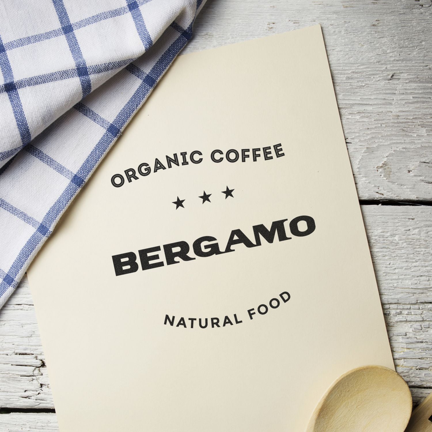 Organic Coffee Bergamo natural food package with brand text, styled on rustic wood and blue check cloth.