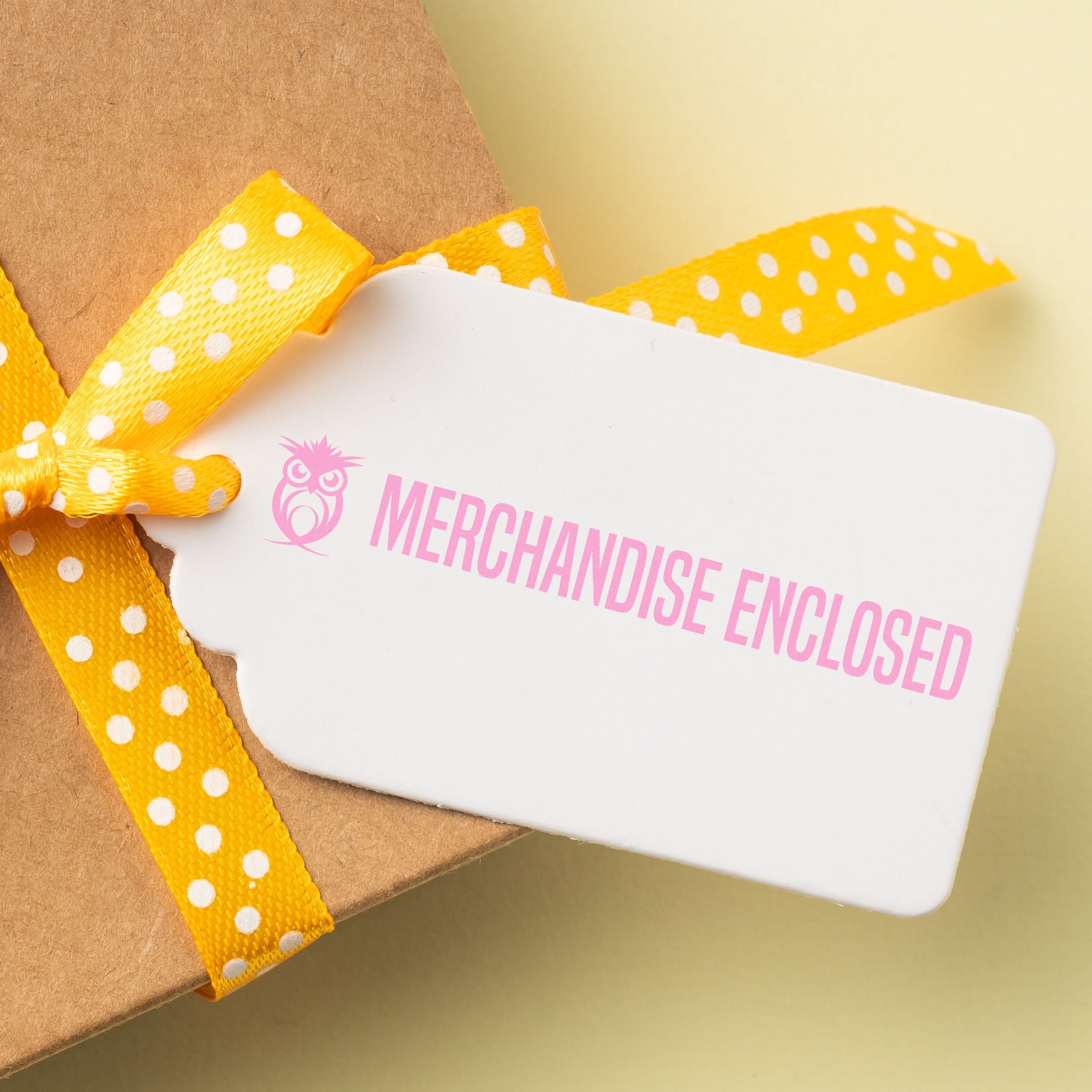 Gift box with Merchandise Enclosed card, yellow polka dot ribbon, and brown kraft packaging.