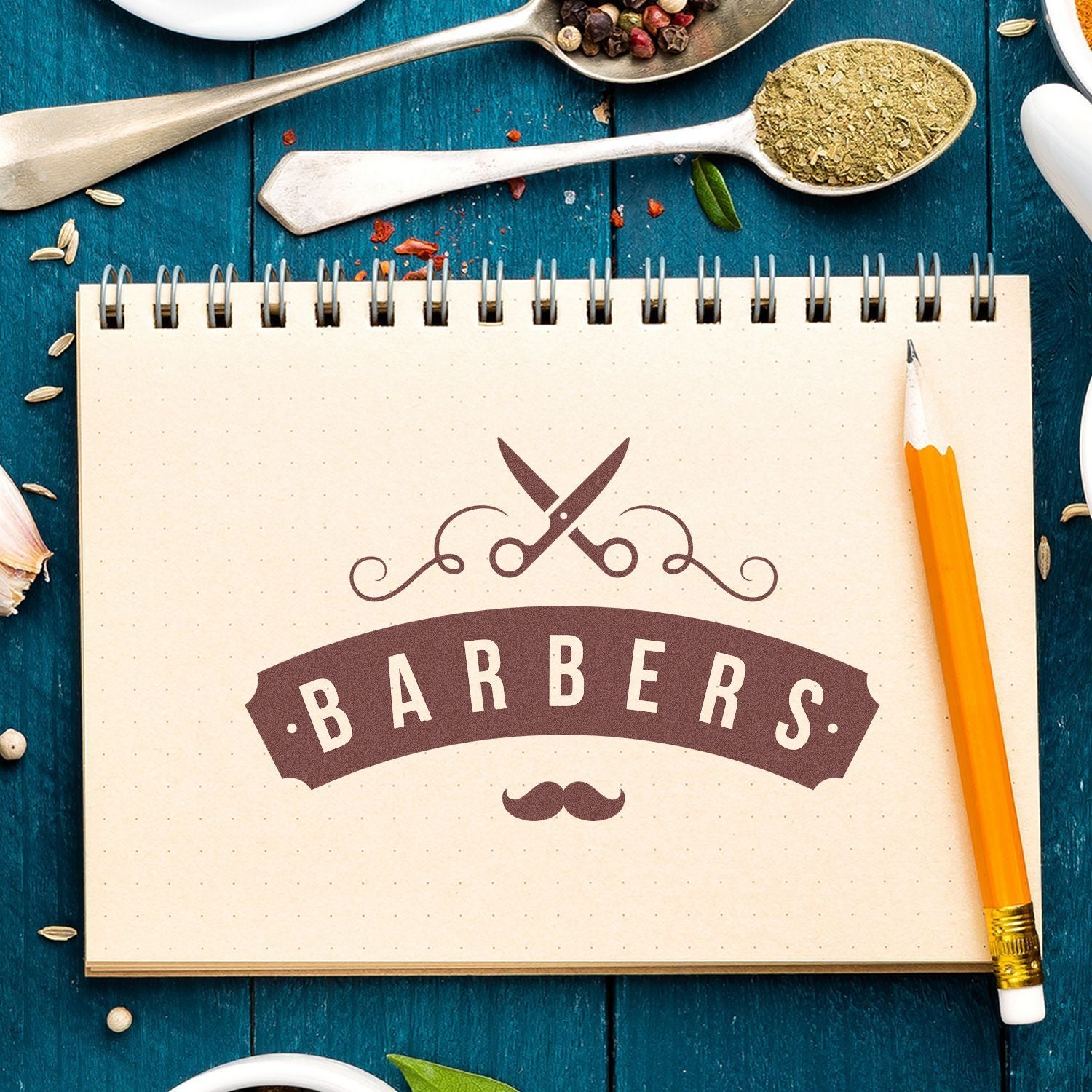 Barbers themed recipe notebook with scissors icon, pencil and kitchen spices on a blue wooden table for barbers cooking branding