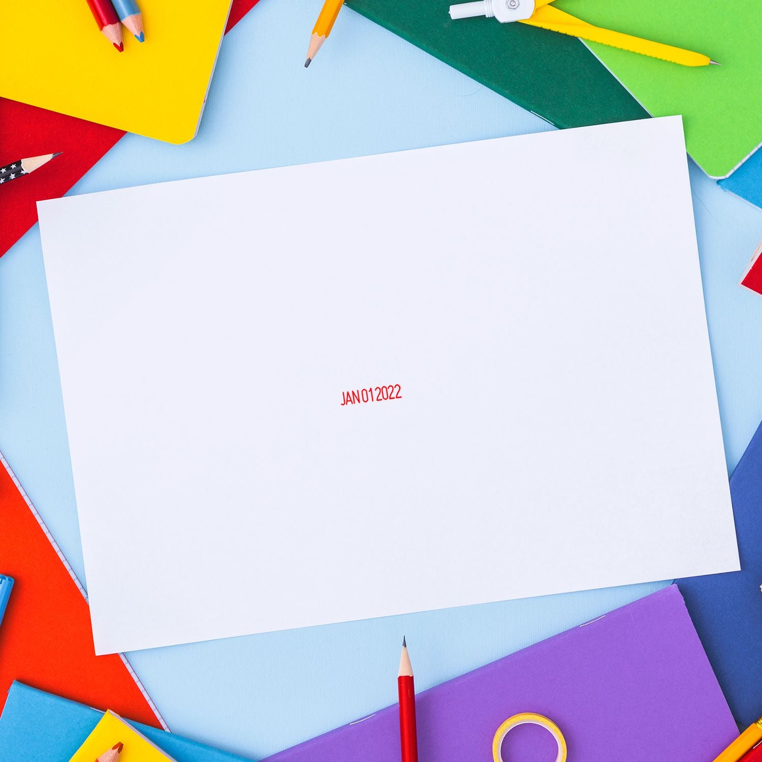 Blank white paper mockup surrounded by colorful pencils, notebooks, and school stationery on a blue background.