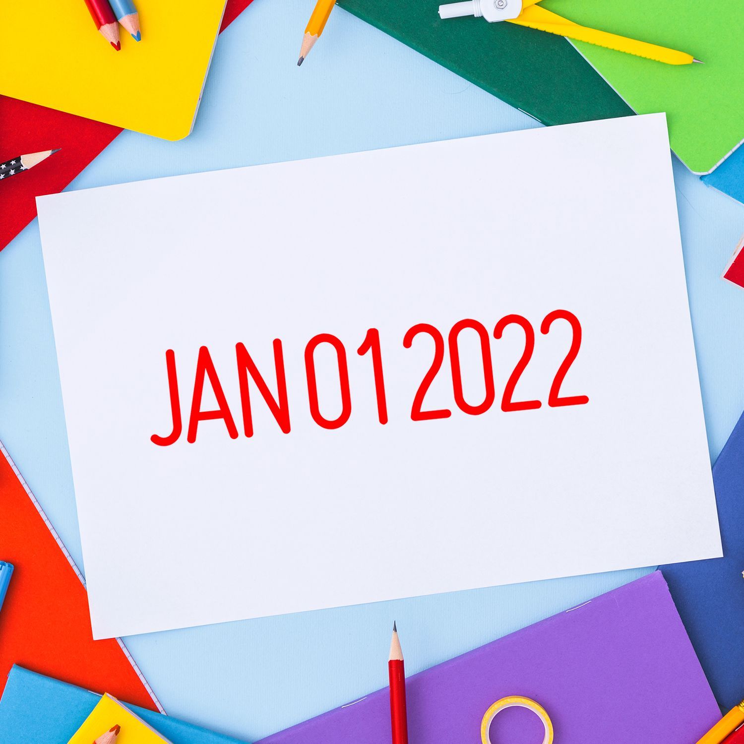 Colorful stationery and notebooks around a blank paper with JAN 01 2022 text, back to school calendar concept