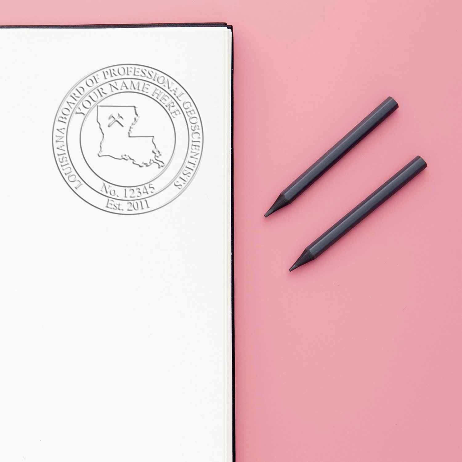 Custom embossed notebook with Louisiana professional geoscience seal and two black pencils on a pink background