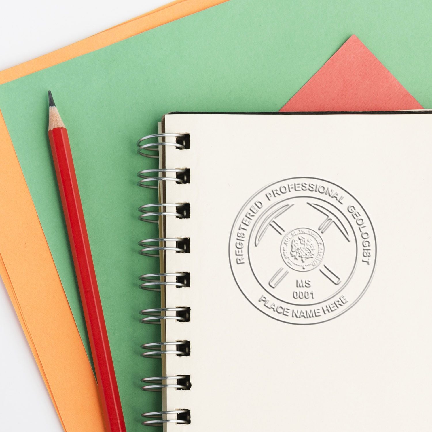 Red pencil beside a spiral notebook stamped “Registered Professional Geologist” on a colorful paper background.