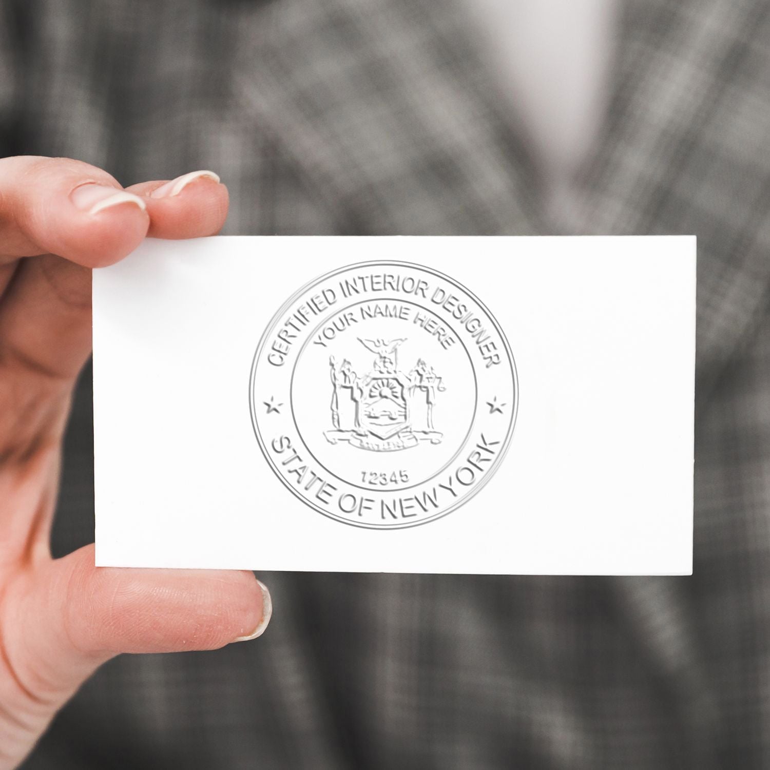 Hand holding a certified interior designer business card with embossed New York State seal.