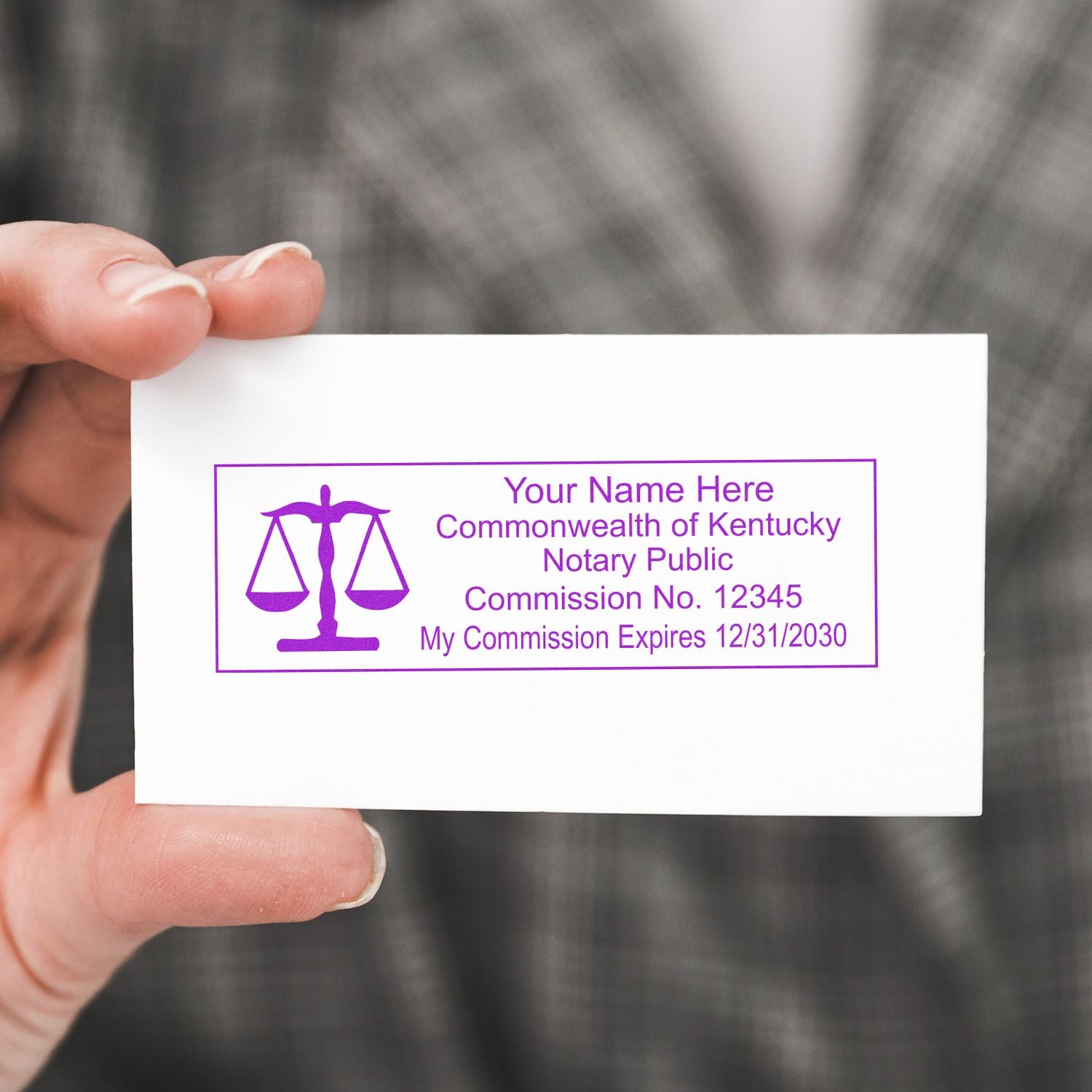 Hand holding a Kentucky Notary Public business card with purple scales of justice logo and commission details.