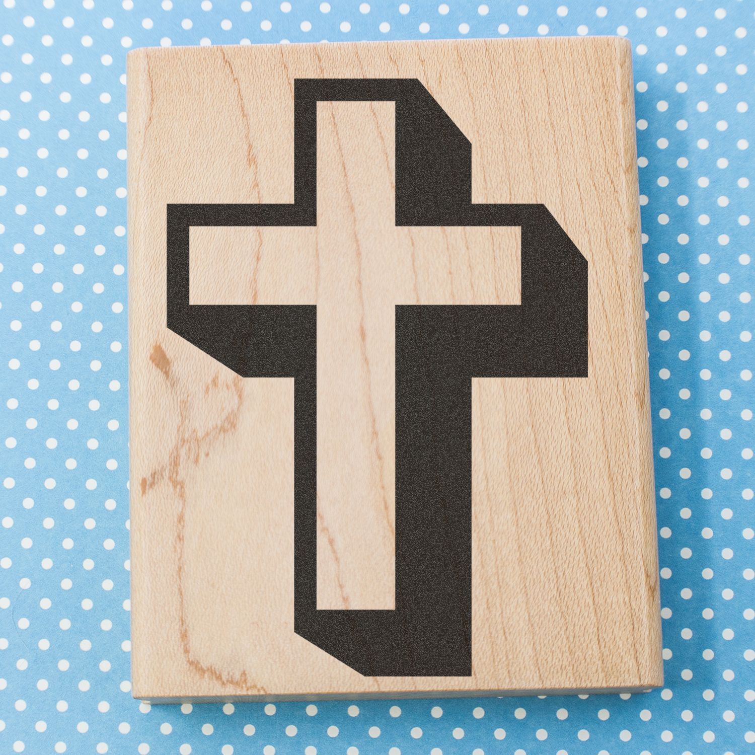 Wooden block with black cross symbol on blue polka dot background